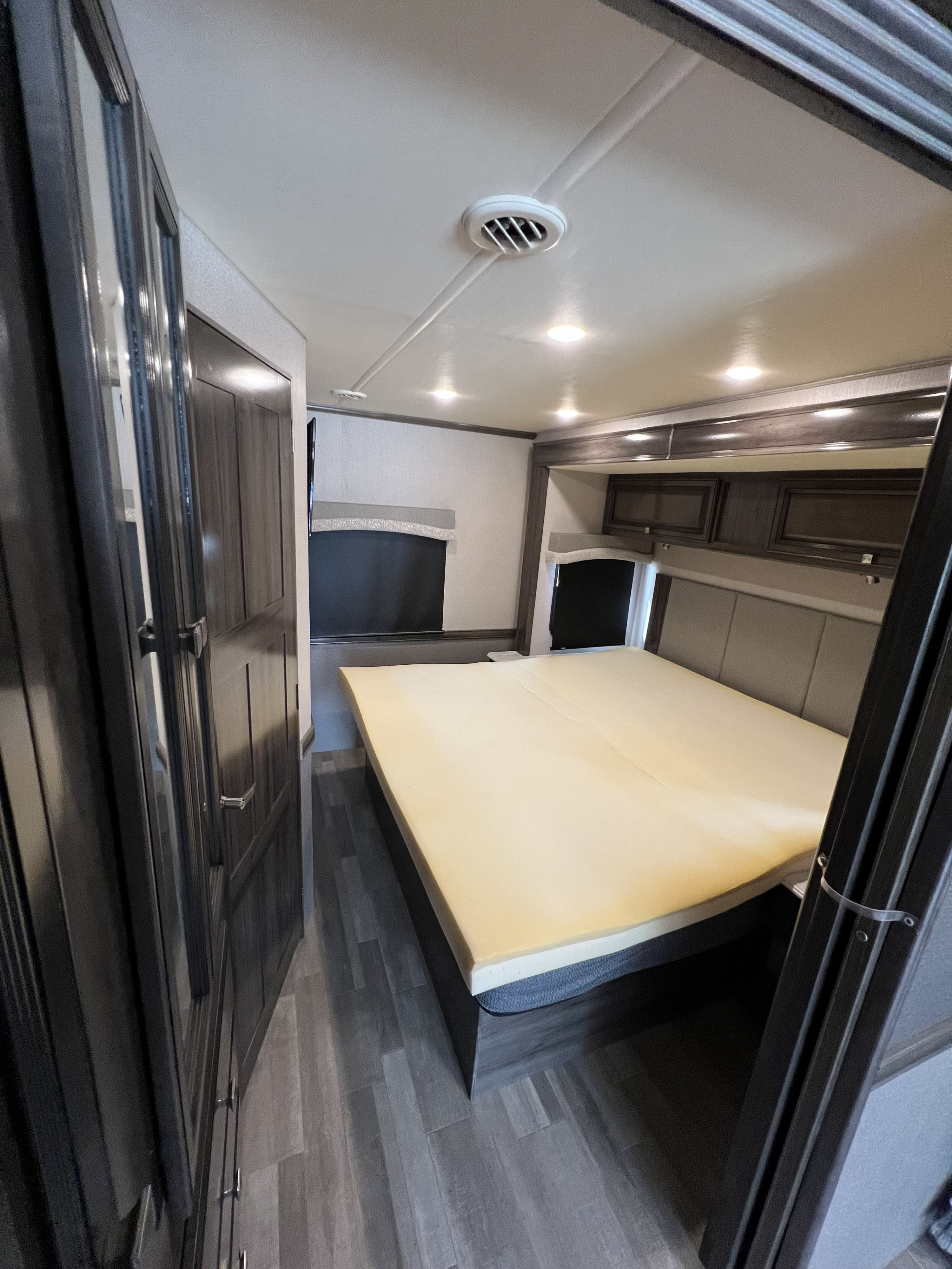 Explore this RV rental bedroom: a modern, comfortable space with a large bed, overhead storage, and entertainment.. Flair-Fleetwood Flair-Fleetwood Motorhome 2020