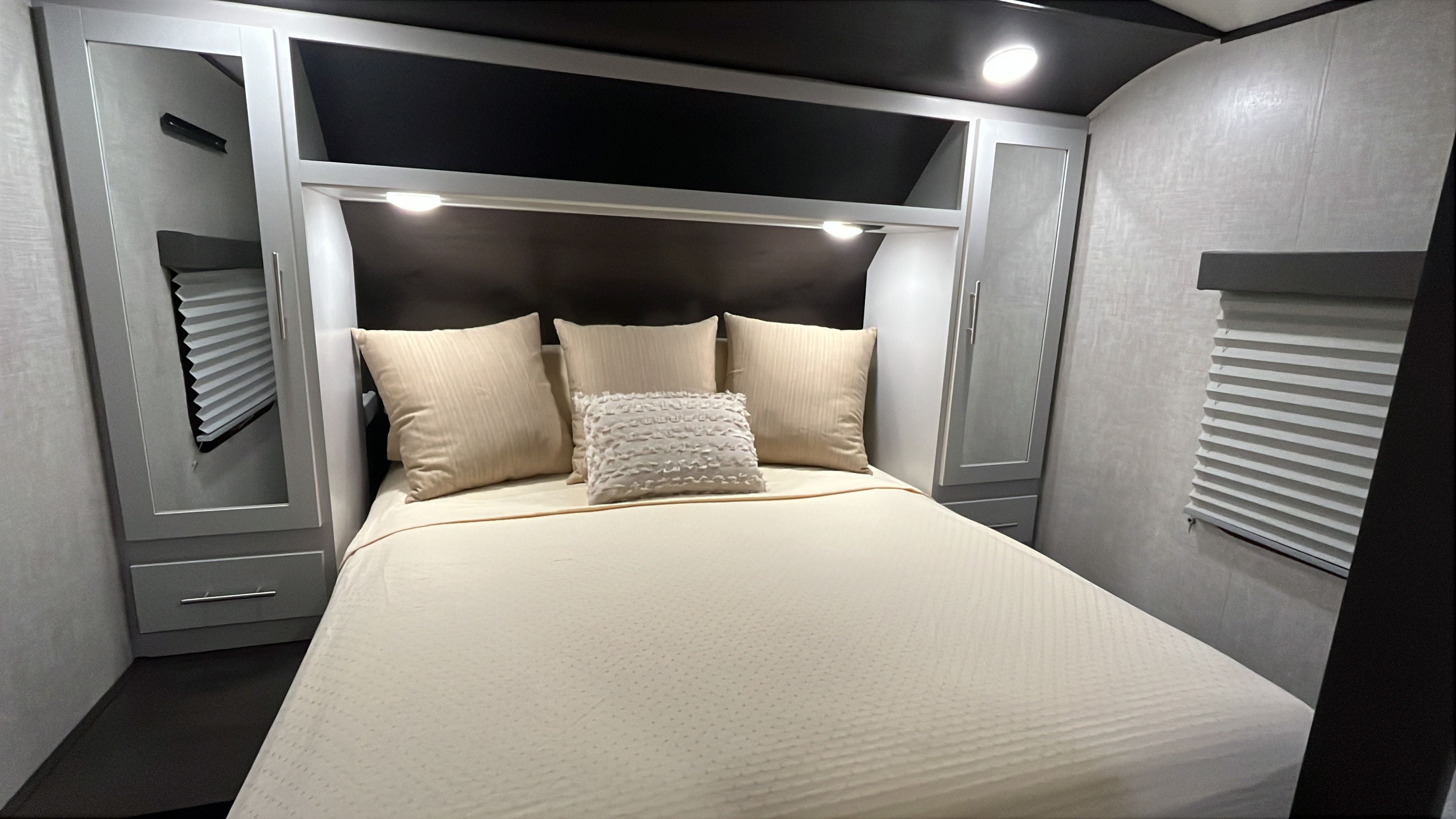 Modern RV rental bedroom featuring a cozy bed with soft pillows, integrated storage, window blinds, and ambient lighting.. Keystone RV Bullet Premier Ultra 2020