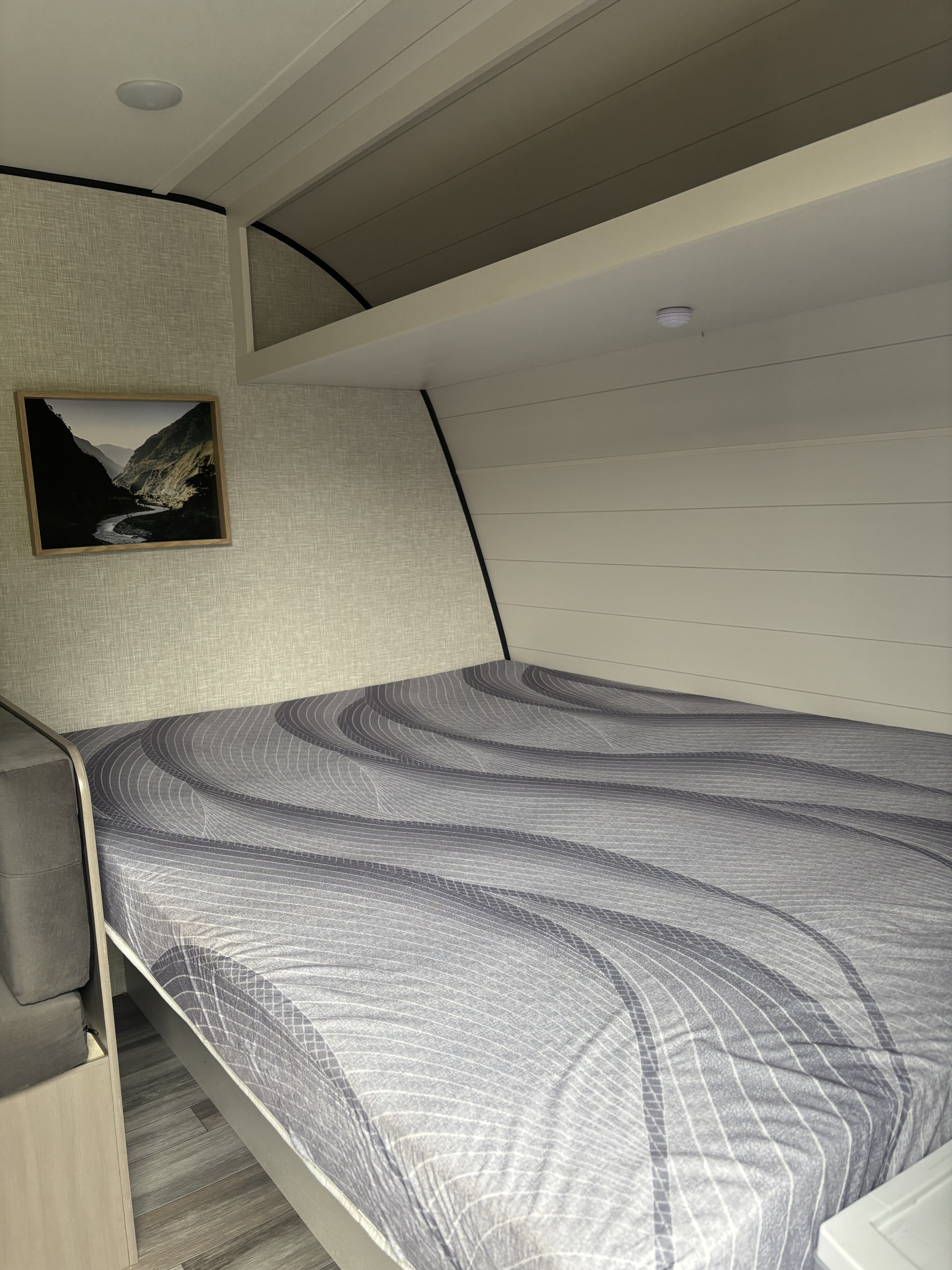 This modern RV rental features a comfortable bed, textured walls, and a scenic mountain artwork, ready for your adventure.. Jayco Jay Feather Air 2025