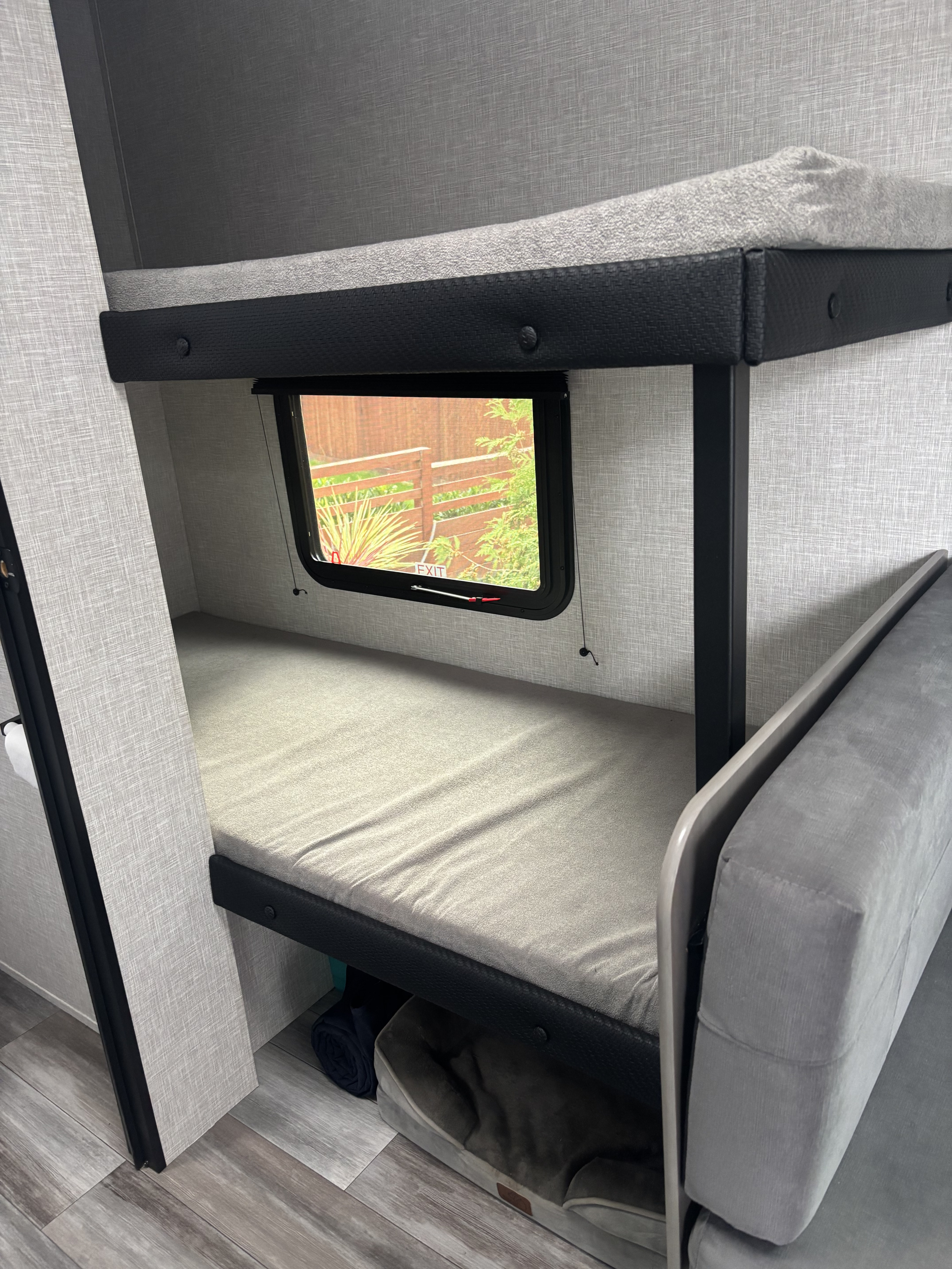 RV rental interior: Light gray bunk beds, a window view, and a dog bed below. Perfect for family travel.. Jayco Jay Feather Air 2025