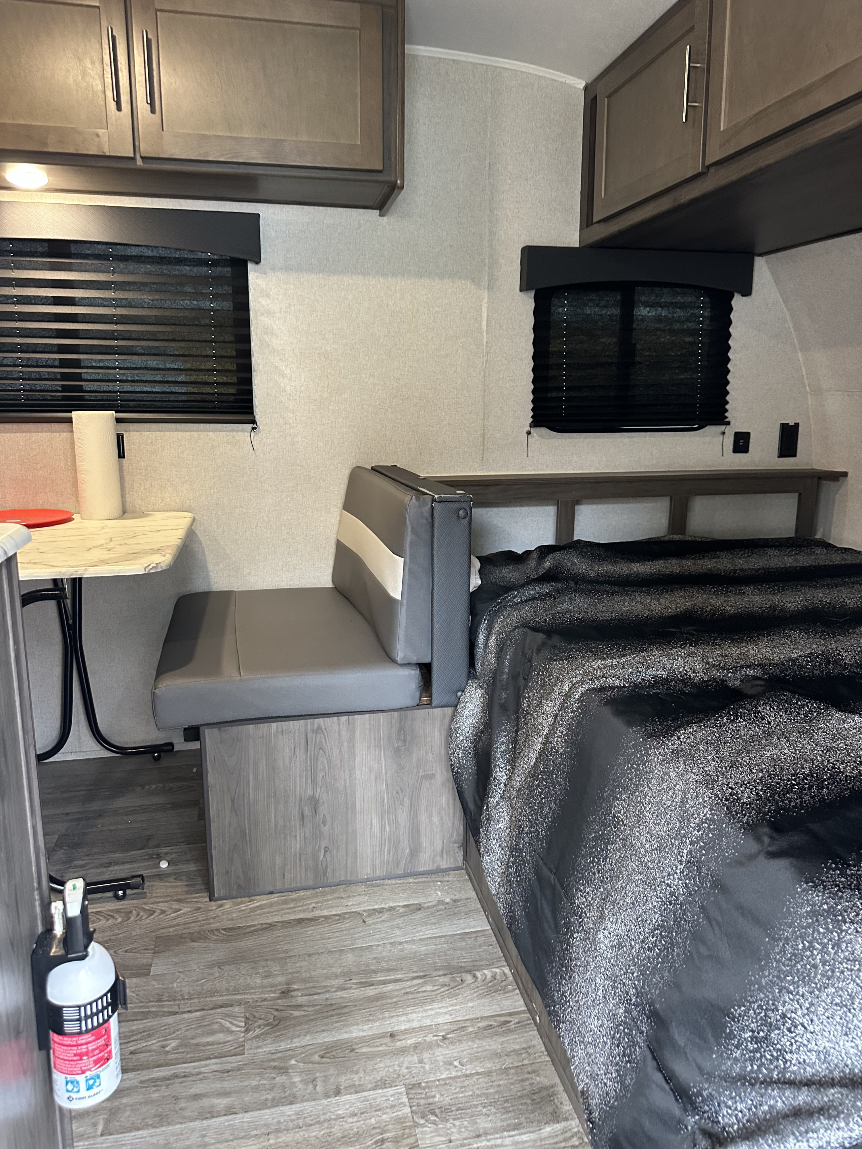 Cozy RV rental interior featuring a compact dining area, bed, and overhead storage. Ideal for travel adventures.. Forest River Viking 2020