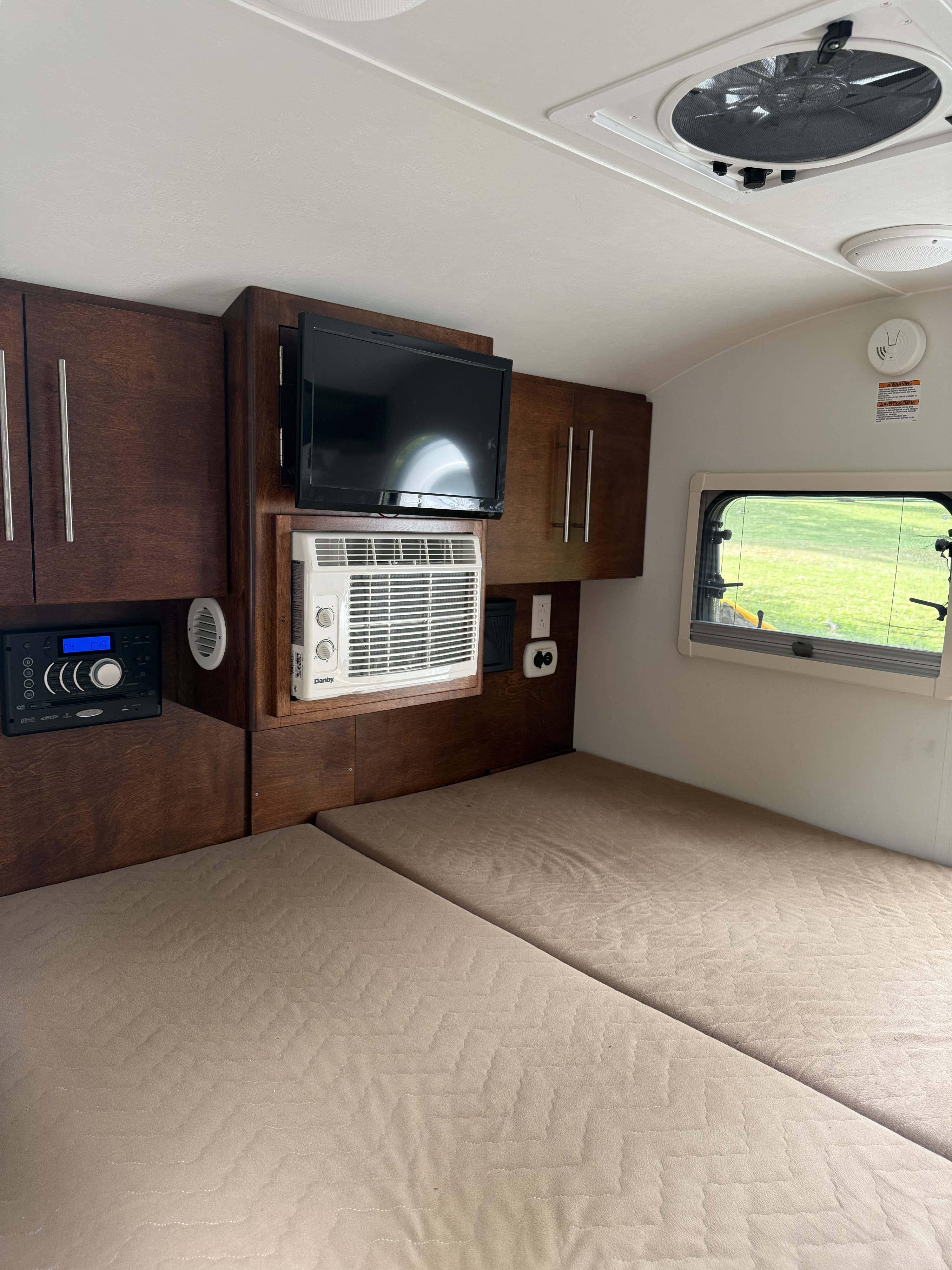 RV rental interior: two beds, TV, AC, and dark wood cabinets. A cozy, compact space ready for travel.. nuCamp T@G 2020