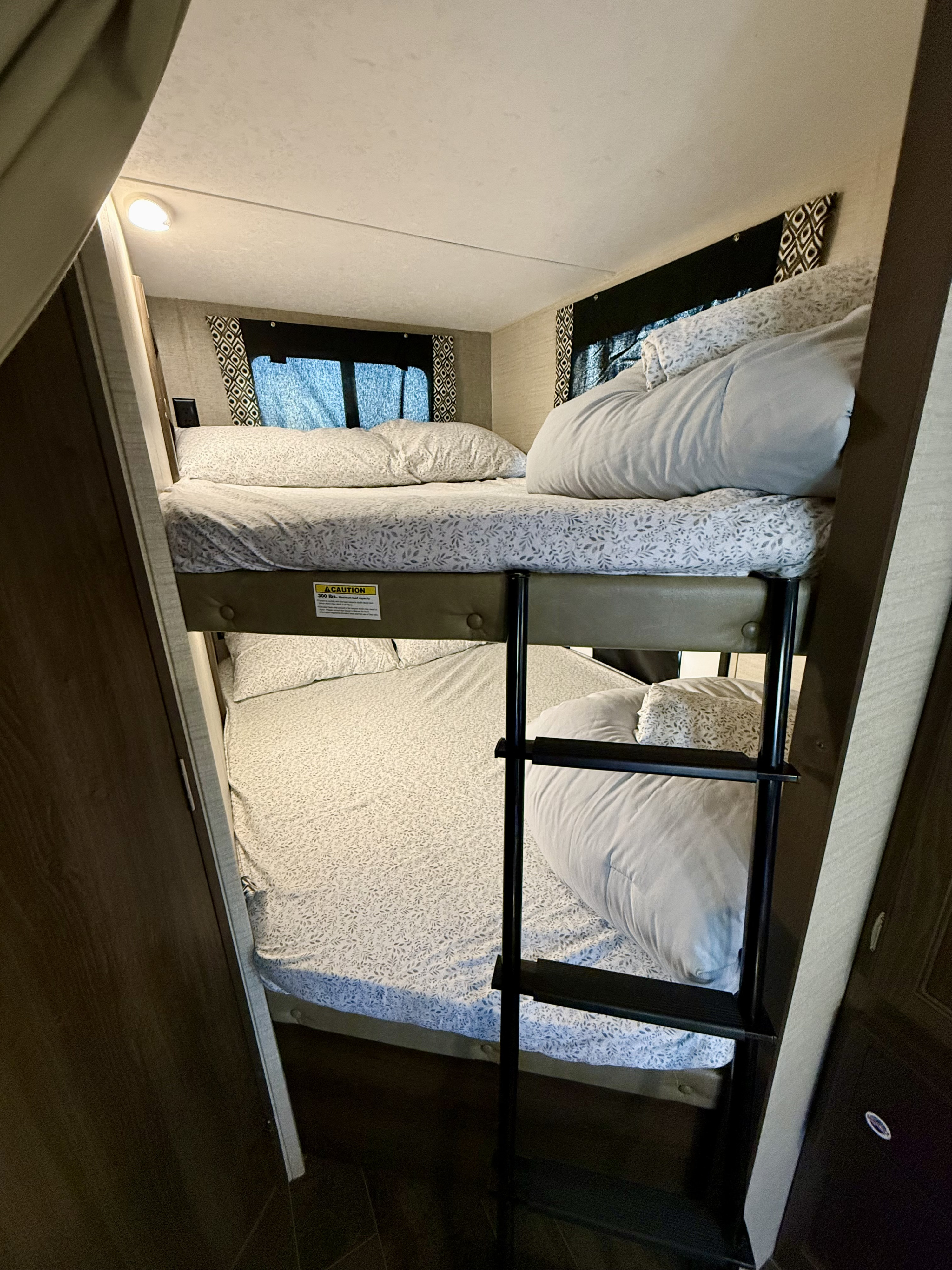 This RV rental features stacked bunk beds, equipped with cozy patterned bedding, pillows, and a safety ladder for easy access.. Keystone RV Bullet Ultra Lite 2018