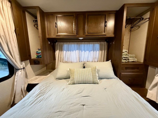 Cozy RV rental bedroom featuring a comfortable bed, overhead cabinets, and built-in wardrobes, ideal for travel comfort.. Forest River Coachmen Freelander 2018