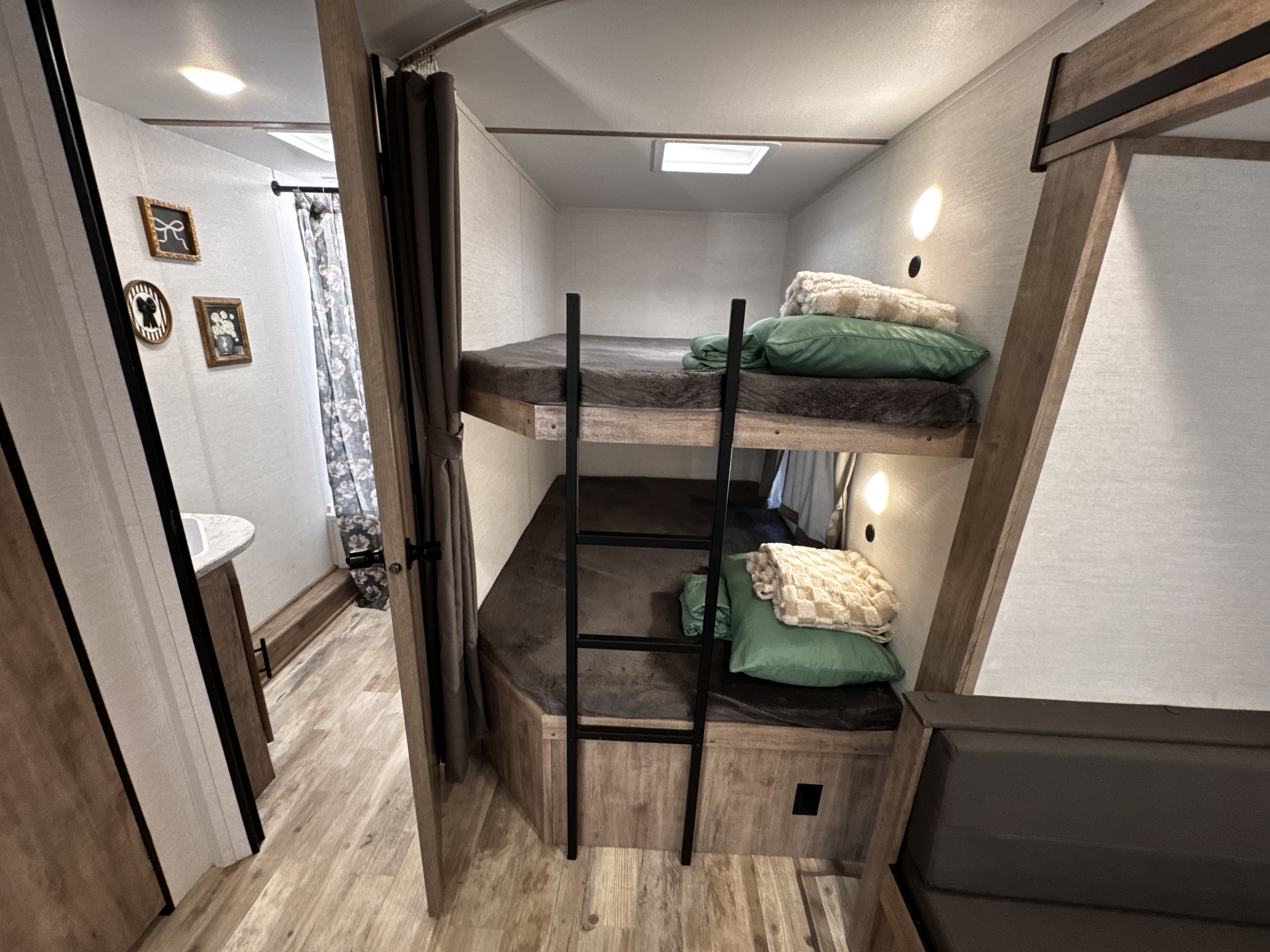 This inviting RV rental features comfortable bunk beds with a ladder, soft pillows, and blankets, ideal for a cozy travel stay.. Gulf Stream Enlighten 2025
