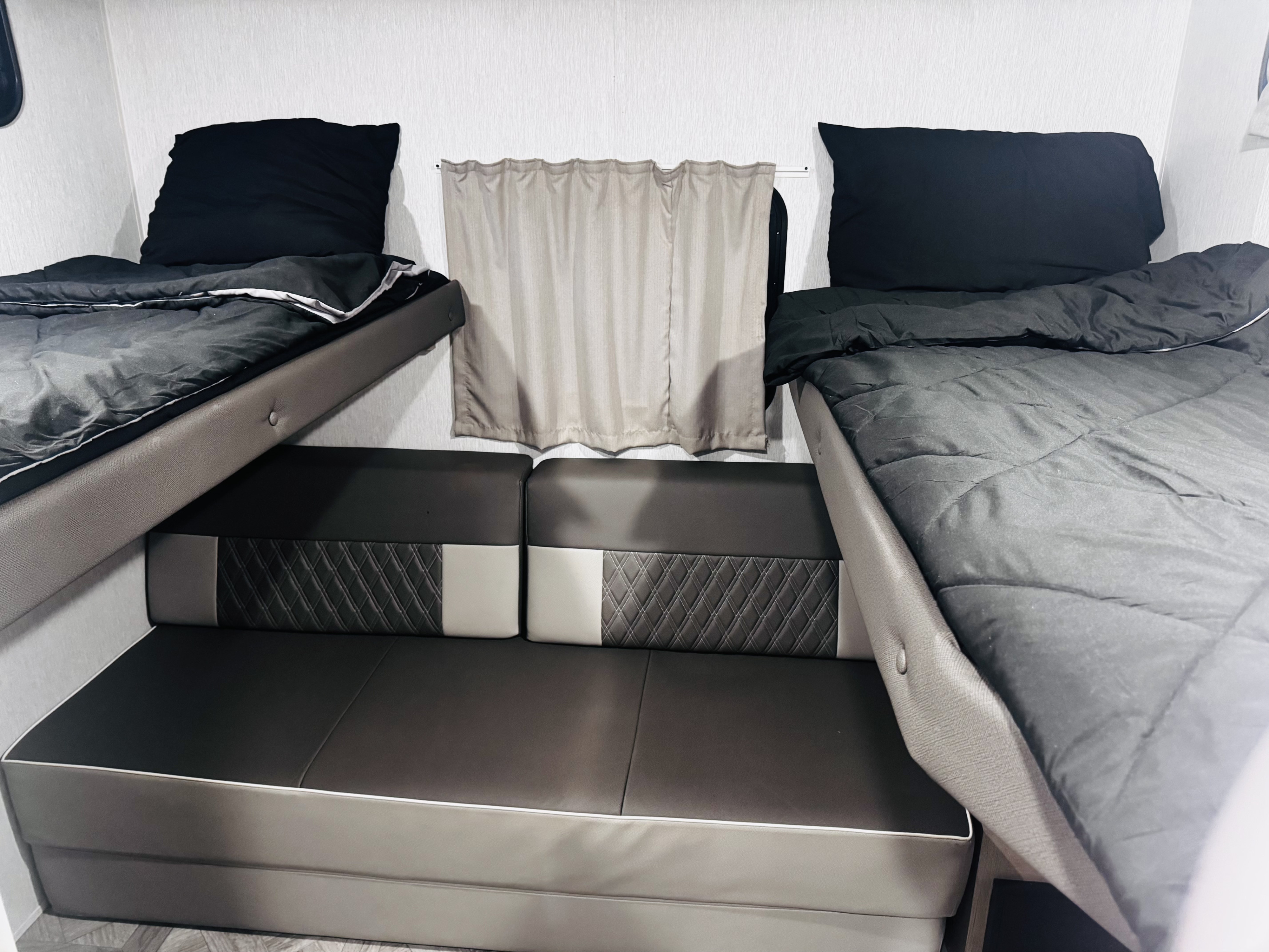 RV rental interior with cozy bunk beds & sofa seating. Perfect for comfortable travel and camping stays.. Forest River Wildwood X-Lite 2023