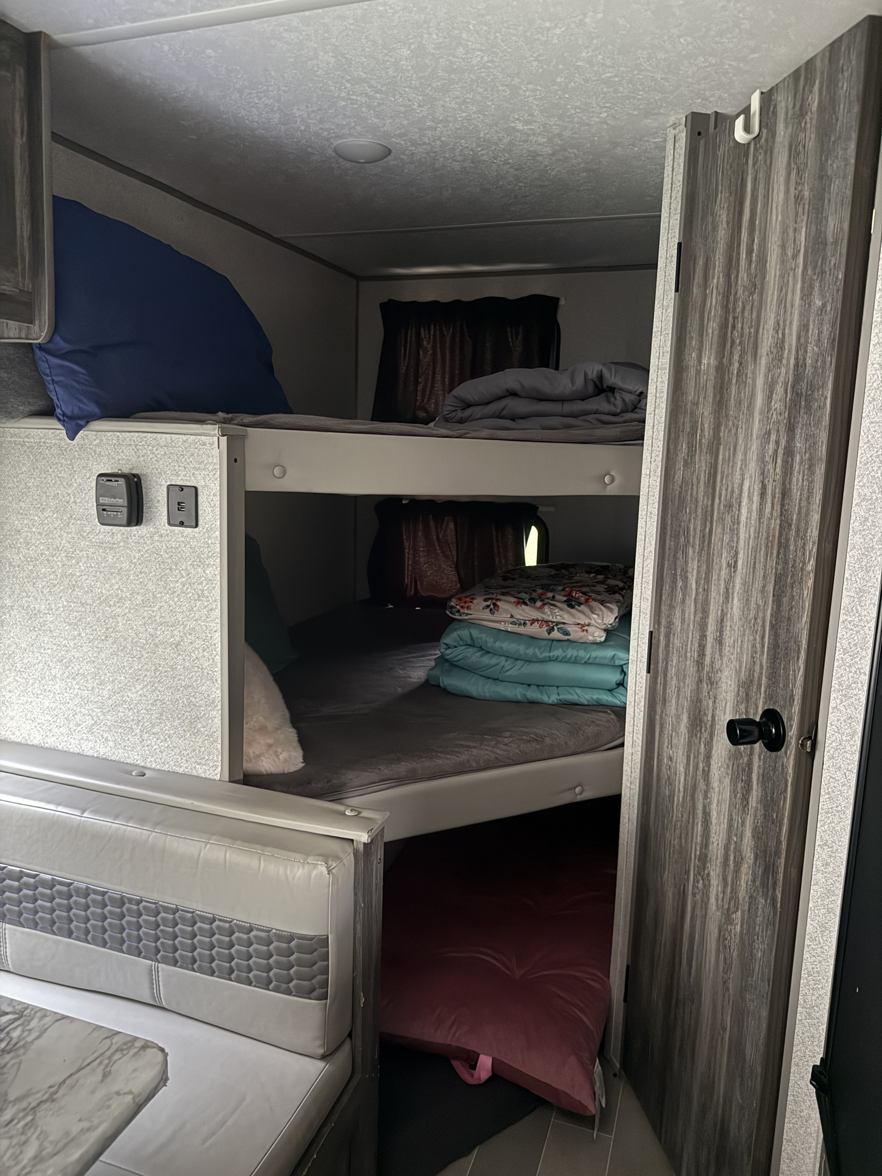 Inside an rv rental, featuring bunk beds on the right, a dinette on the left, and a door on the far right.. Forest River Salem FSX 2020