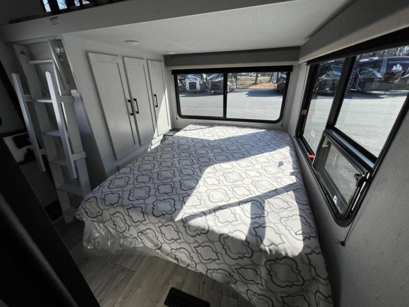 Spacious RV rental bedroom with a comfy bed, storage cabinets, and a ladder to a loft area, ideal for travel.. Astoria Astoria Fifth Wheel 2023