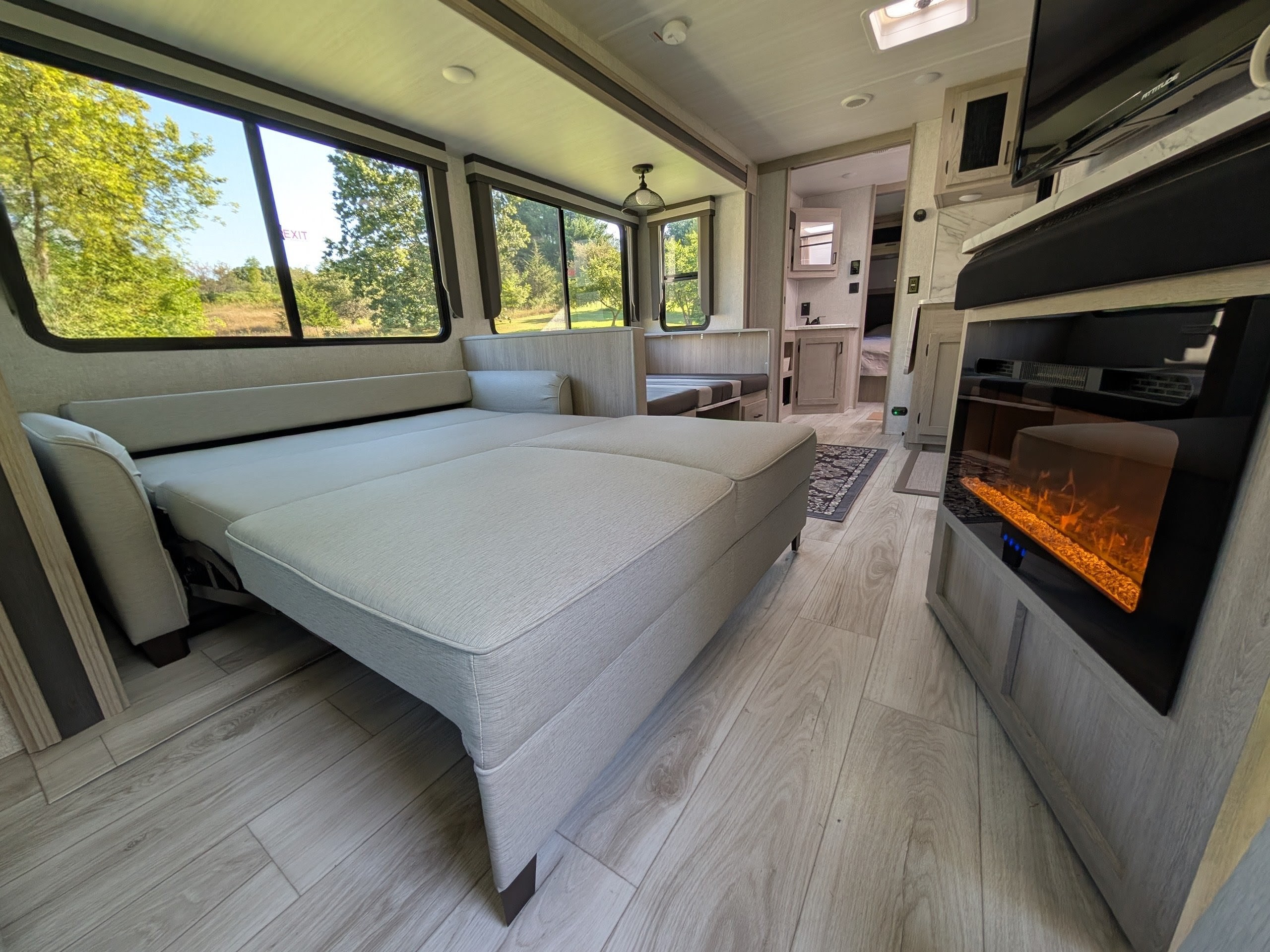 Spacious RV rental living area featuring a pulled-out sofa bed, scenic windows, and an electric fireplace.. Forest River Alta 2850KRL 2025