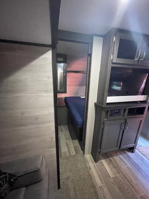 **RV rental interior:** living space with couch, entertainment center, and a glimpse into a bedroom with a blue mattress.. Jayco Jay Flight SLX 2021