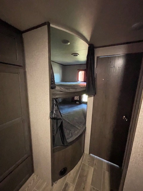 Cozy RV rental bunk beds: Compact interior featuring stacked sleeping areas with dark bedding, a door, and wood-look flooring.. Jayco Jay Flight SLX 2021