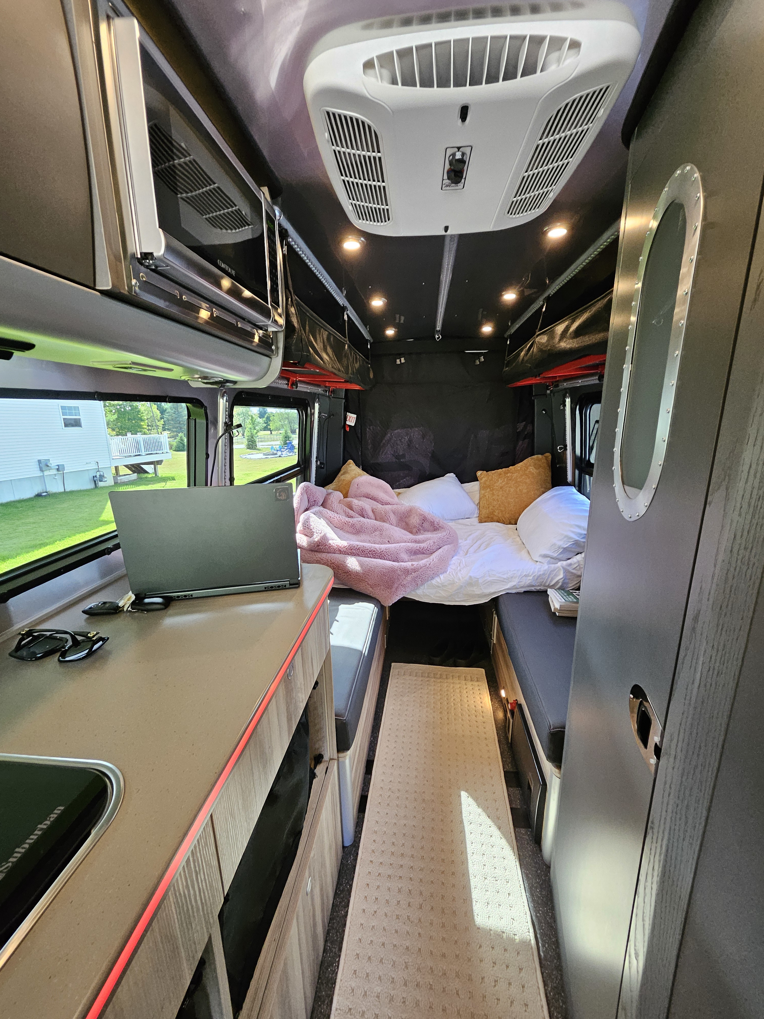 Inside this modern rv rental, a cozy bed, workstation with laptop, full kitchen, microwave, and AC create a comfortable mobile home.. Airstream Interstate 2022