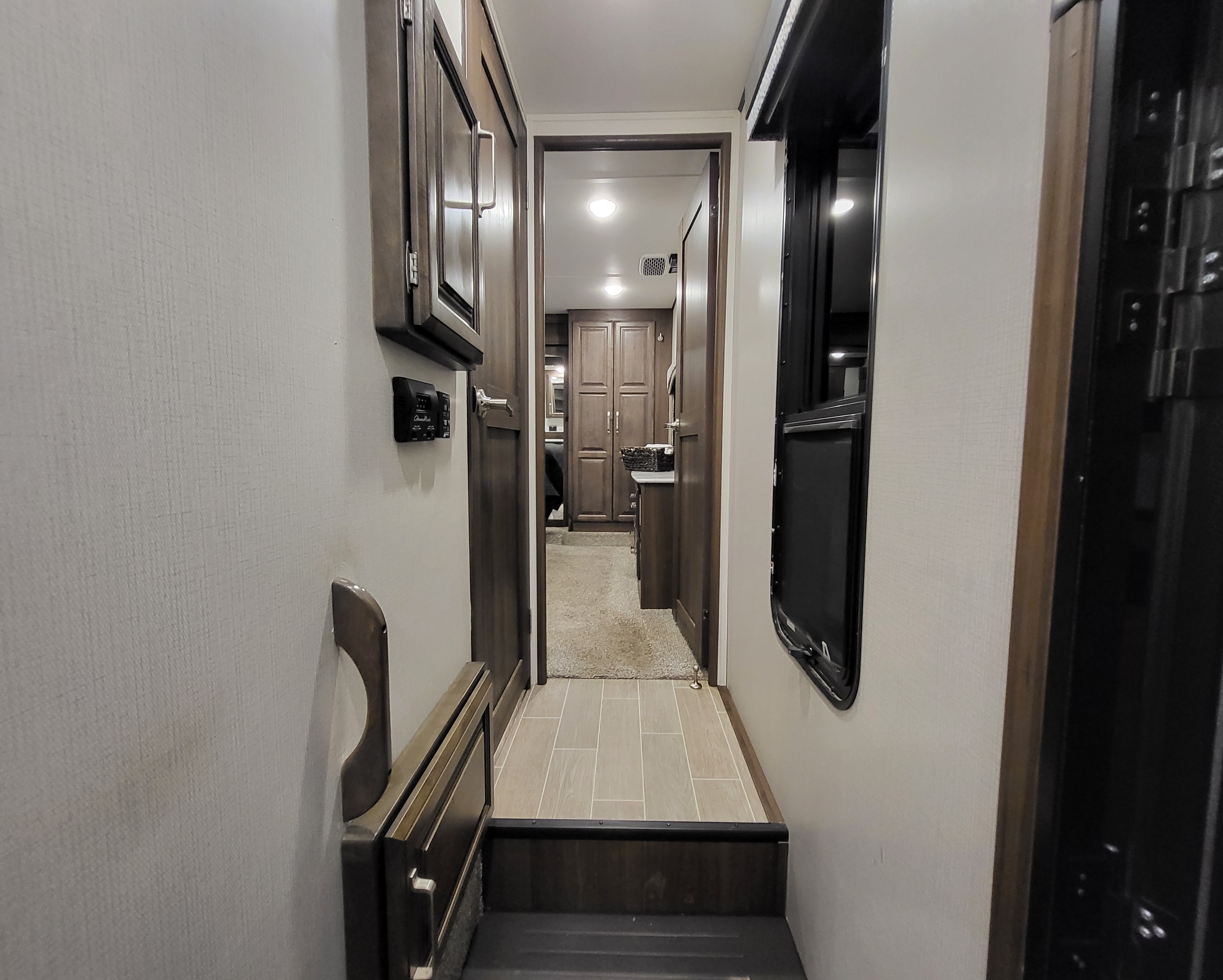 RV rental interior: A hallway with steps leading to a living space with dark wood cabinets and doors.. Keystone Avalanche 2021