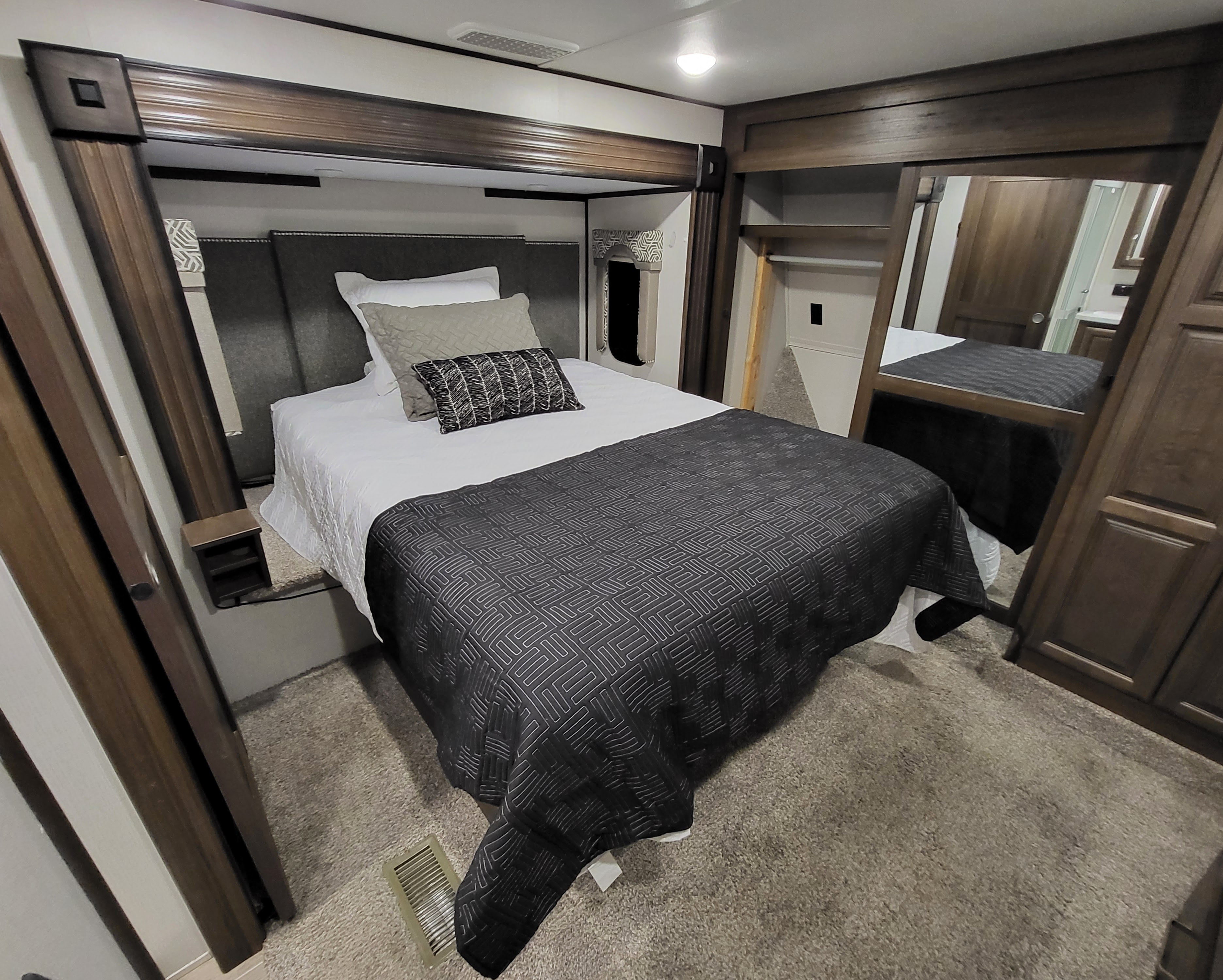 Relax in this cozy RV rental bedroom. Features a queen bed with plush bedding, built-in storage, and wood finishes.. Keystone Avalanche 2021