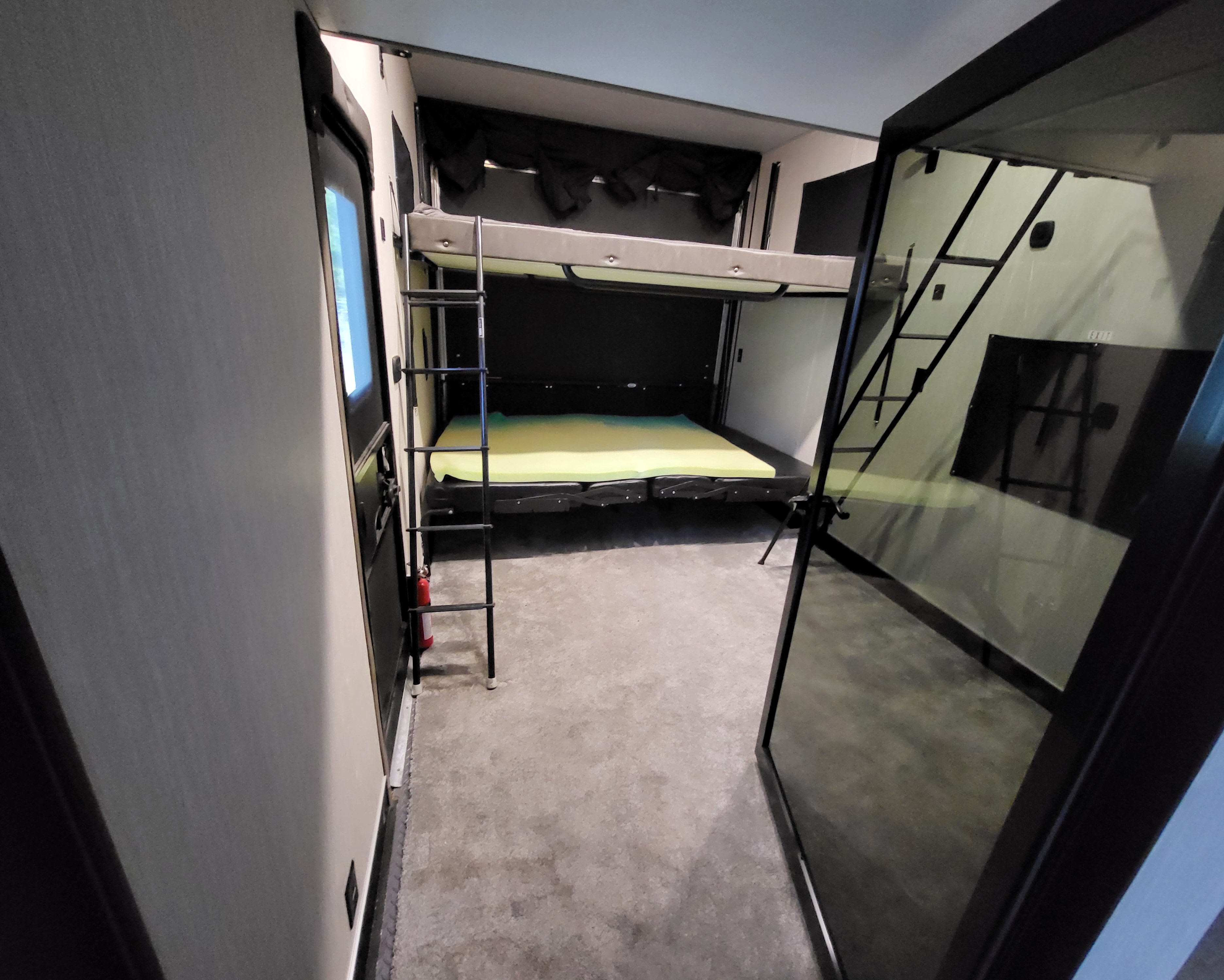 RV rental: Interior shows stacked bunk beds, ladder, foam mattress, & fire extinguisher in a spacious RV cargo area.. Forest River Vengeance 2020