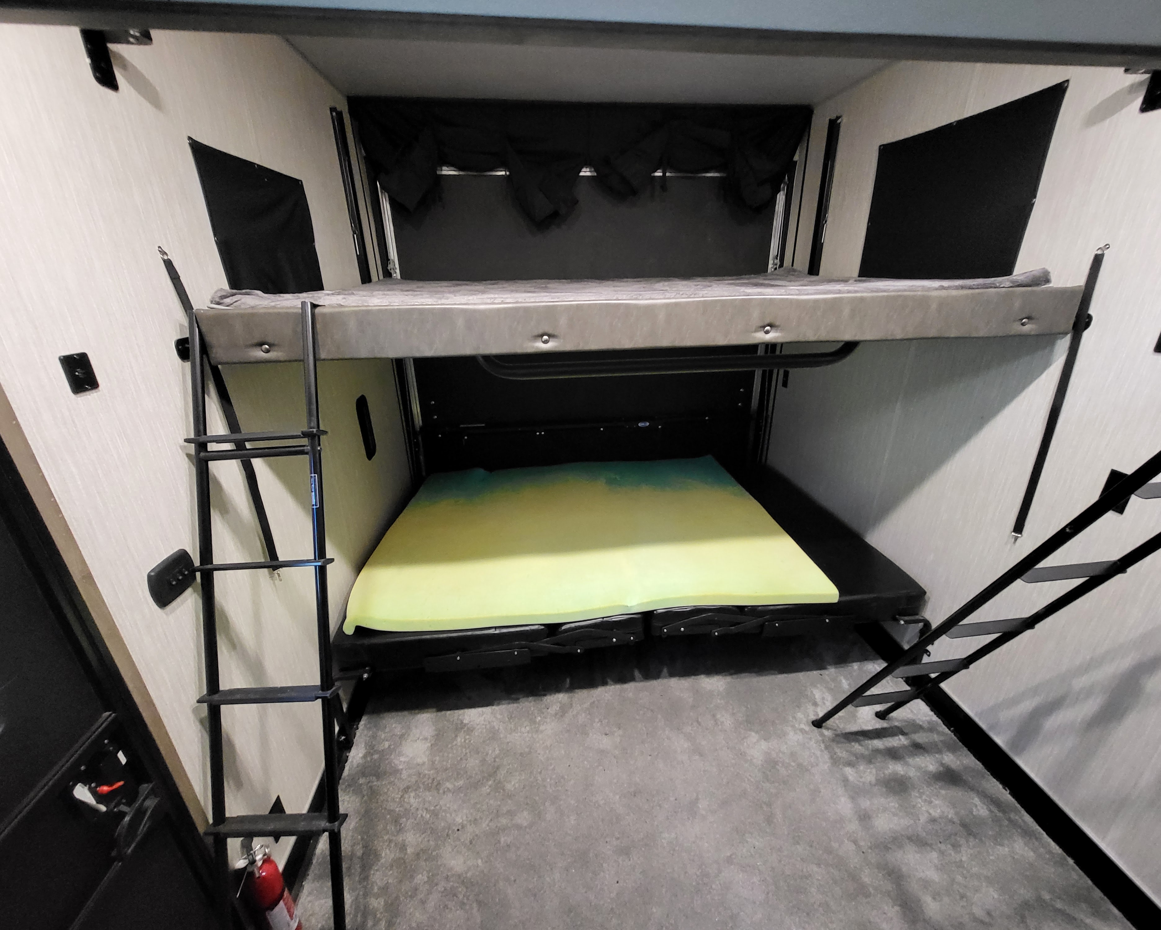 RV rental interior features stacked bunk beds with ladders. The lower bed has a bright green mattress, providing flexible sleeping space.. Forest River Vengeance 2020