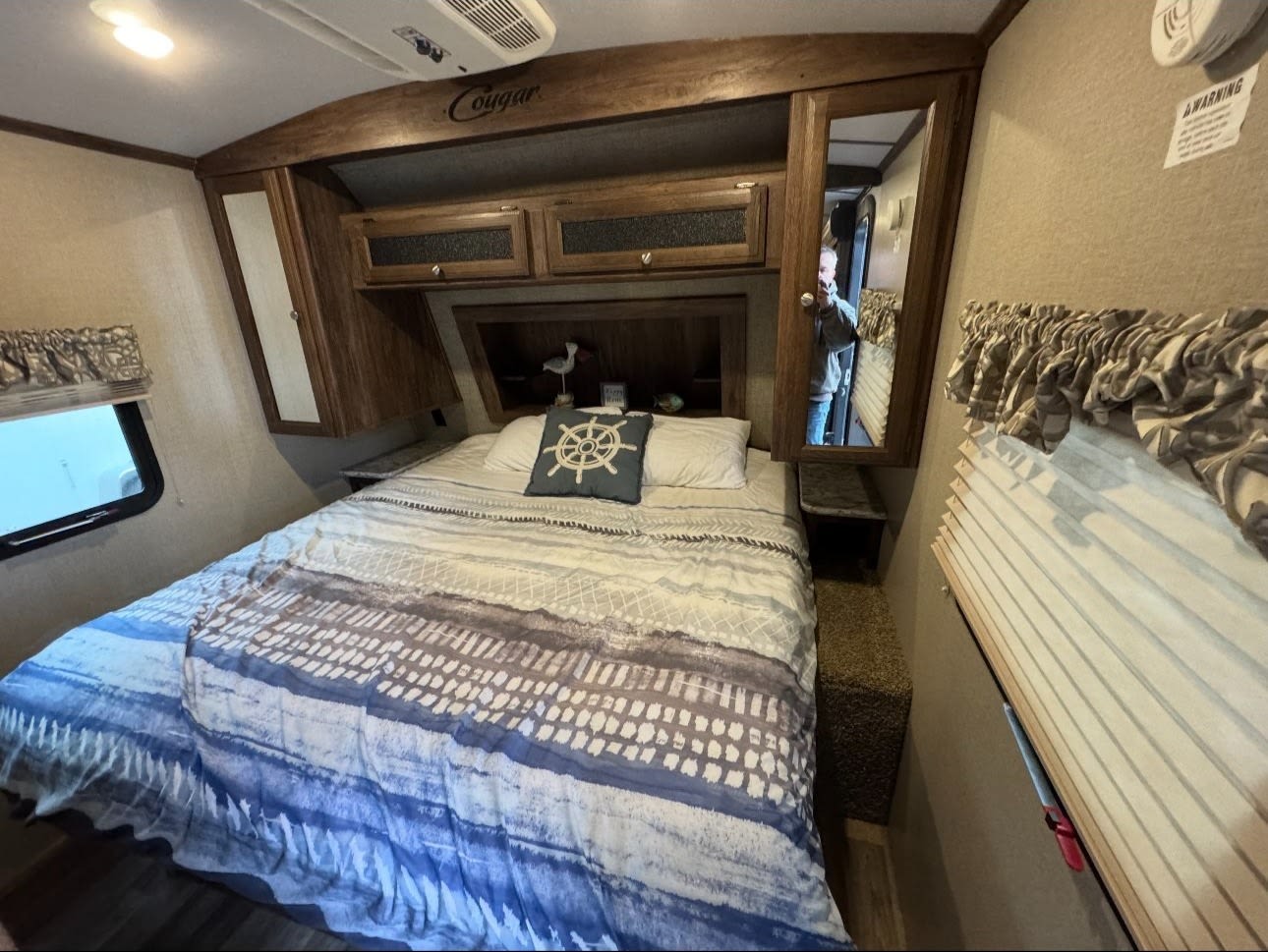 Comfortable RV rental bedroom featuring a full bed, overhead storage, and bright windows. Your perfect road trip stay.. Keystone RV Cougar X-Lite 2018