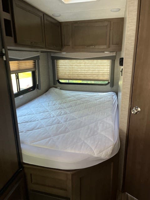 RV rental: A compact bedroom with a quilted bed, overhead cabinets, and shaded windows provides a cozy retreat.. Thor Four Winds 2020