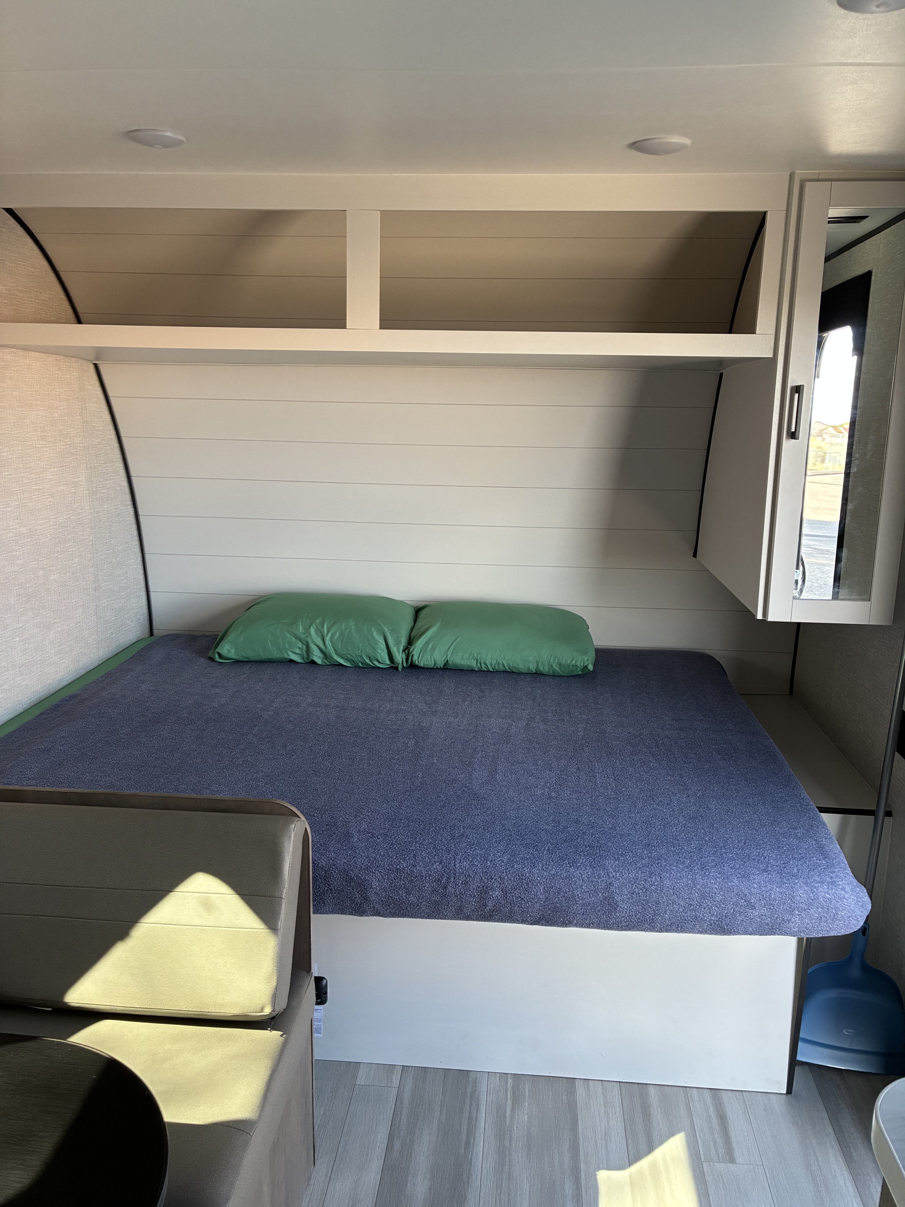 An RV rental bedroom with a blue blanket, green pillows, built-in shelving, and storage cabinet.. Starcraft Ar-One 2026