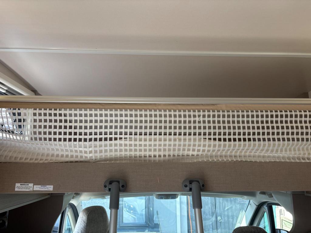 Overhead bunk bed with safety net in an RV rental, located above the driver's cab, ensuring safe and cozy sleeping.. Swift Edge 466 2020