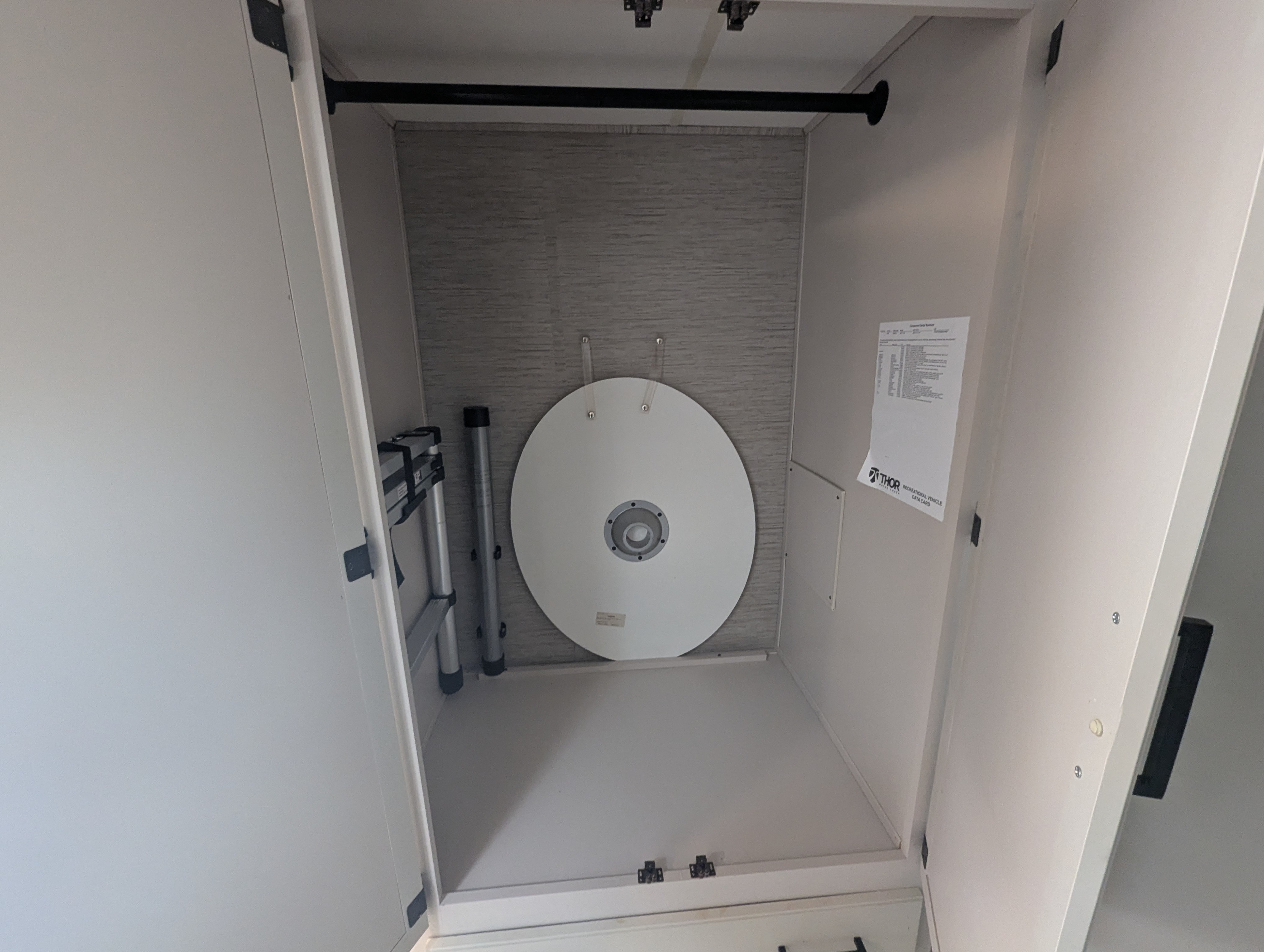 Organized rv rental closet featuring a hanging rod, folded ladder, portable table, and Thor RV data card for guest info.. Thor A.C.E. 2022