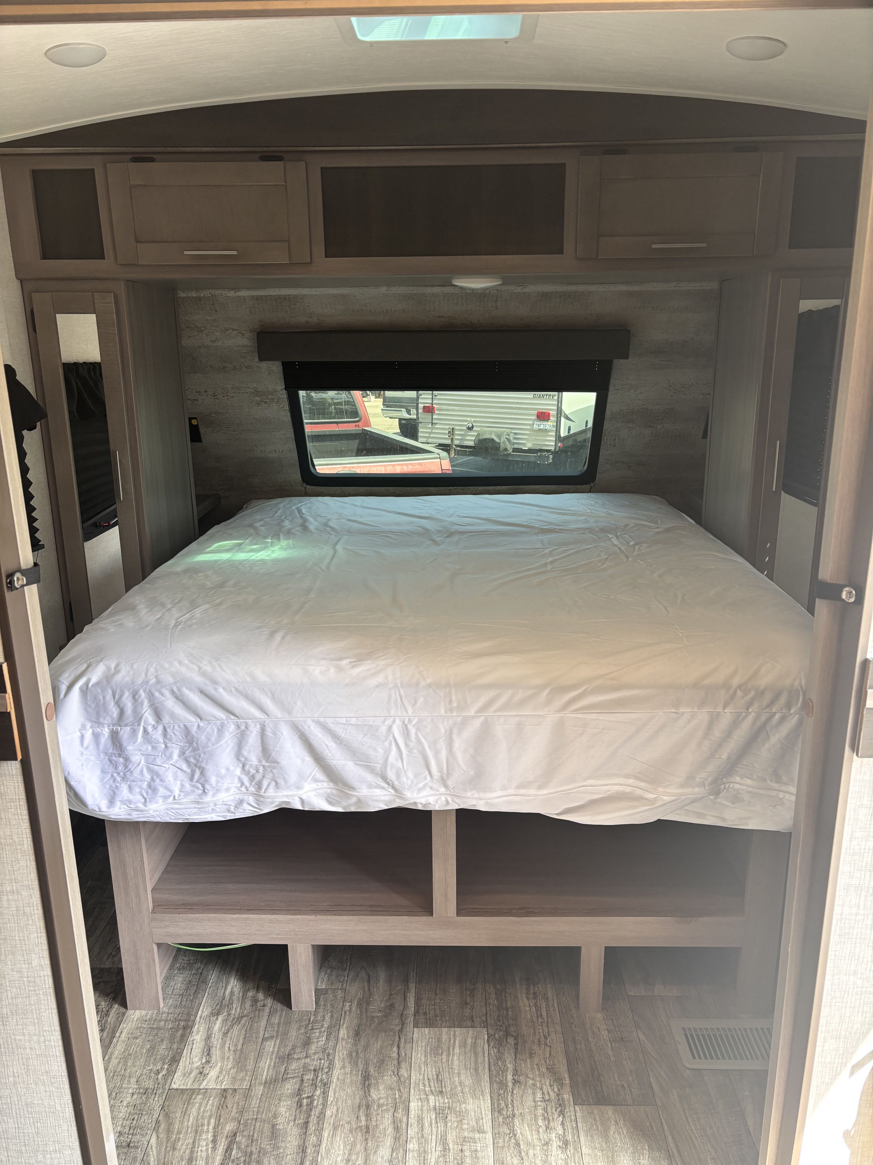 Comfortable RV rental bedroom with spacious bed, overhead storage, and window view for your travels.. Crossroads RV Sunset Trail Super Lite 2022