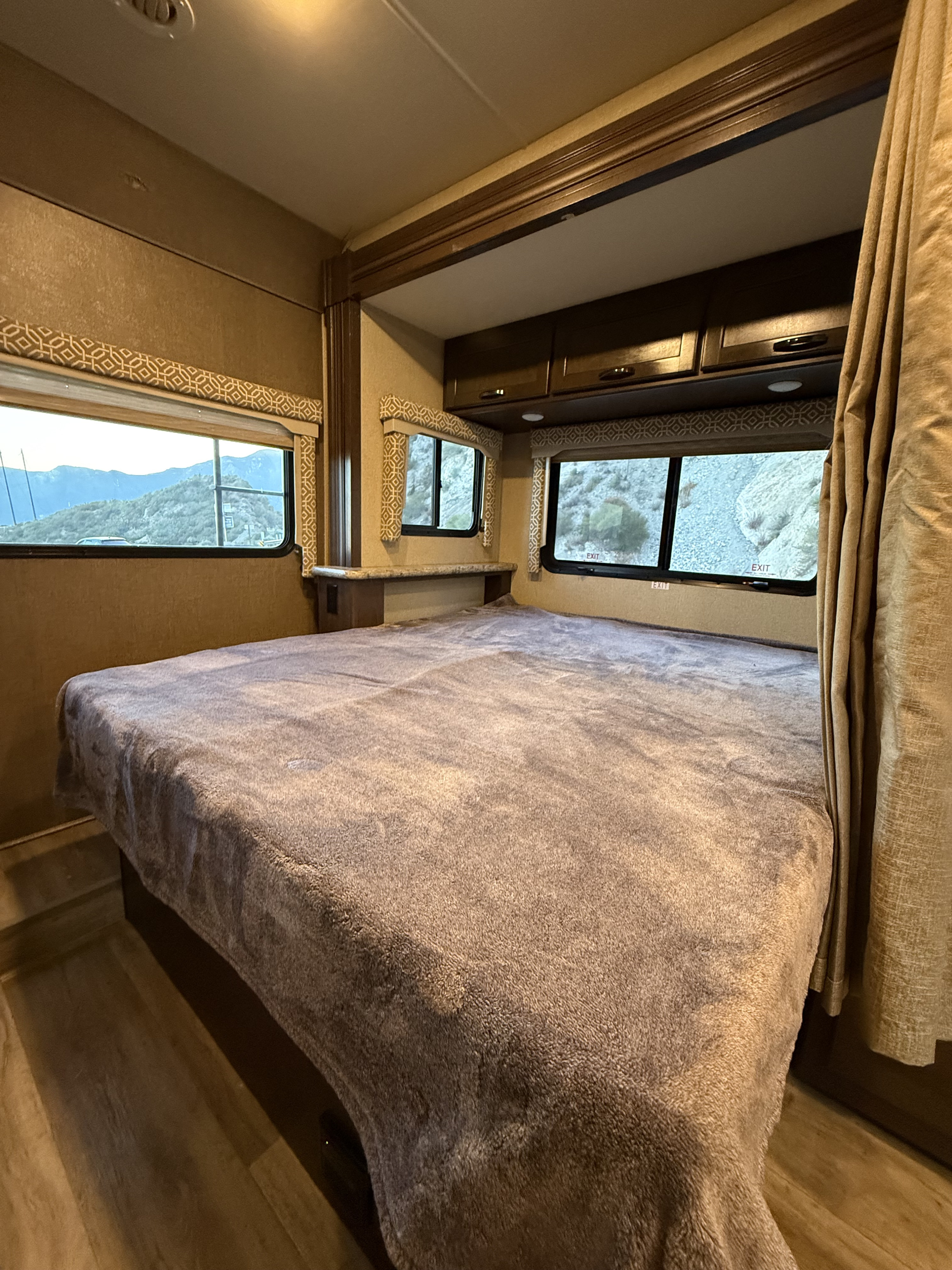 Inside a cozy RV rental bedroom: plush bed, scenic mountain views, and overhead storage for a comfortable journey.. Mercedes-Benz Freedom Elite 2017