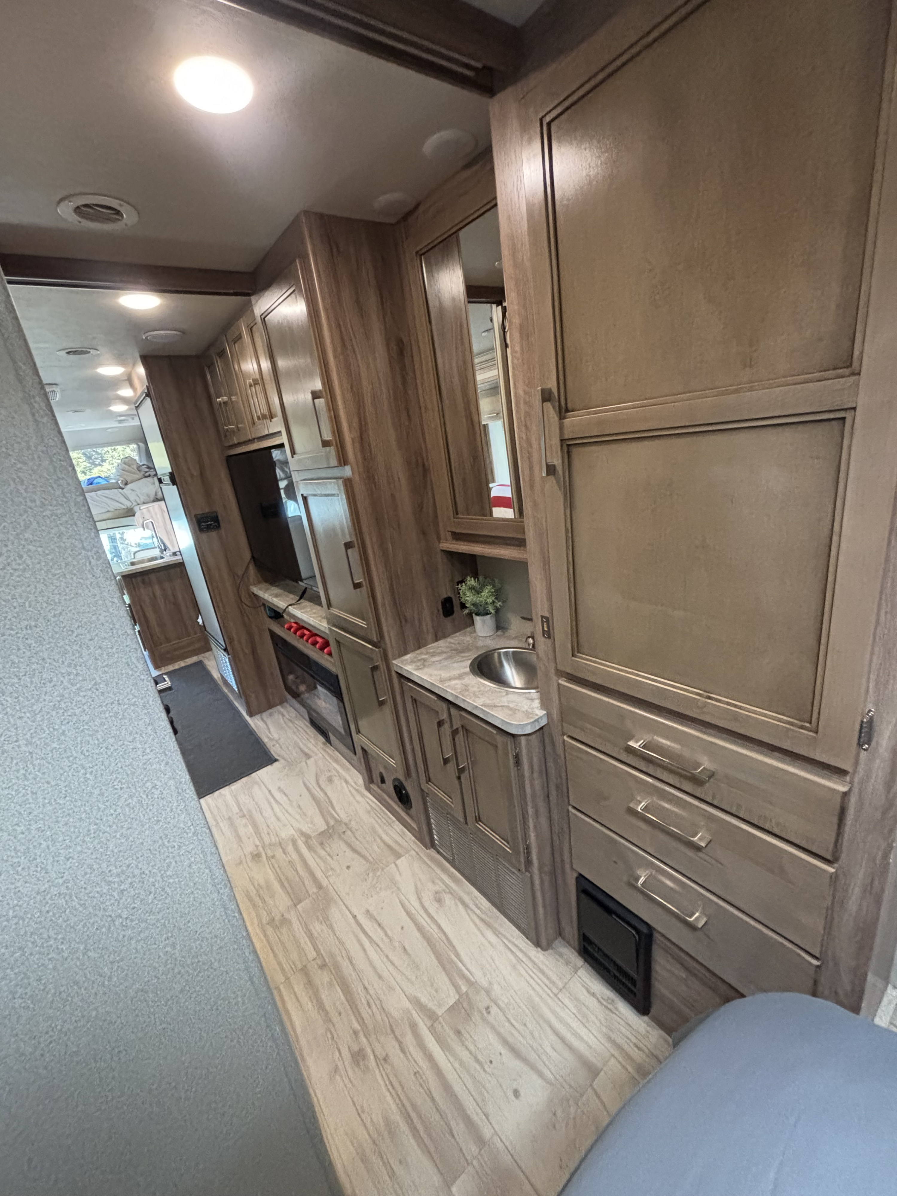 Inside a modern rv rental, featuring wood cabinetry, a small sink, and cozy sleeping areas, perfect for travel.. Entegra Coach Odyssey 2019