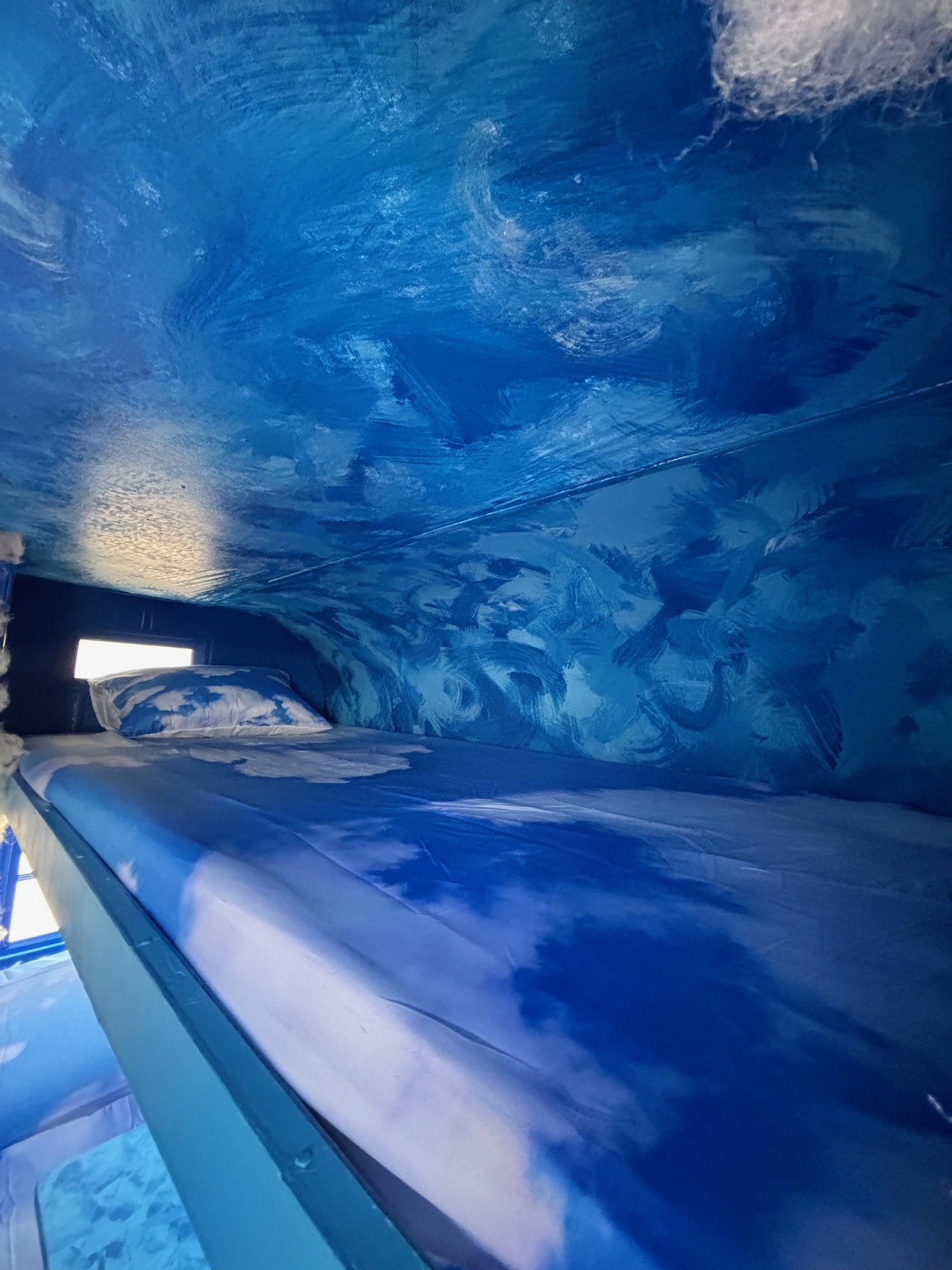 Cozy, cloud-themed bunk bed interior in an RV rental, offering a unique sleeping experience with blue walls and bedding.. Warn The West Fluffy The Cloud 2025