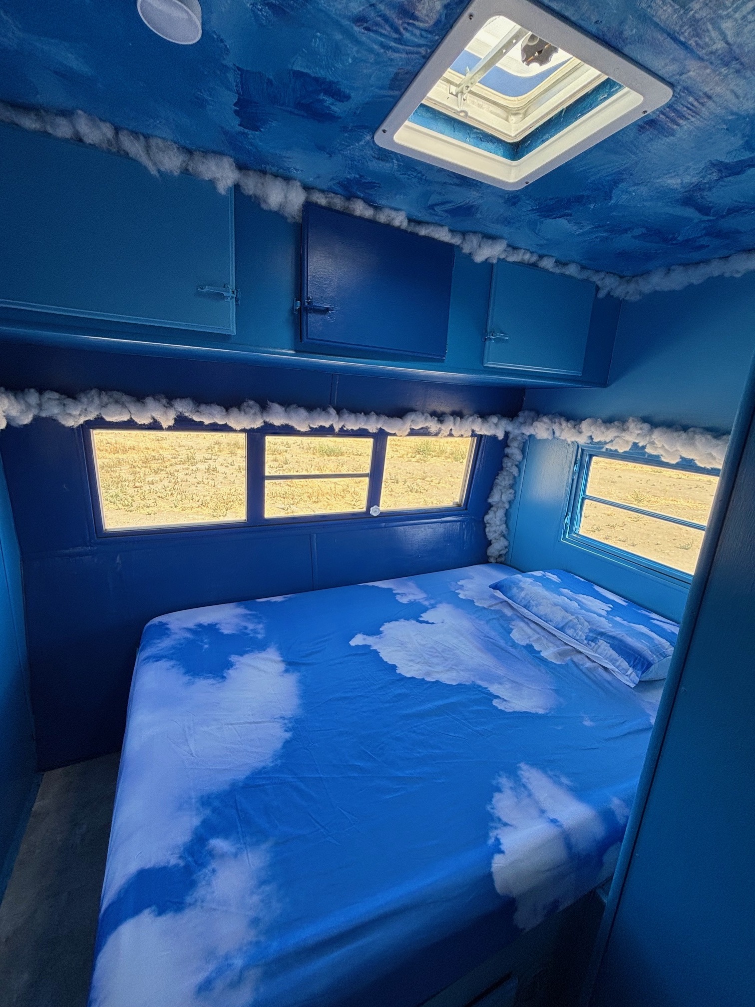 Dreamy blue RV rental interior with a cloud-themed bed, sky-like ceiling, and fluffy cloud trim creates a unique, serene escape.. Warn The West Fluffy The Cloud 2025