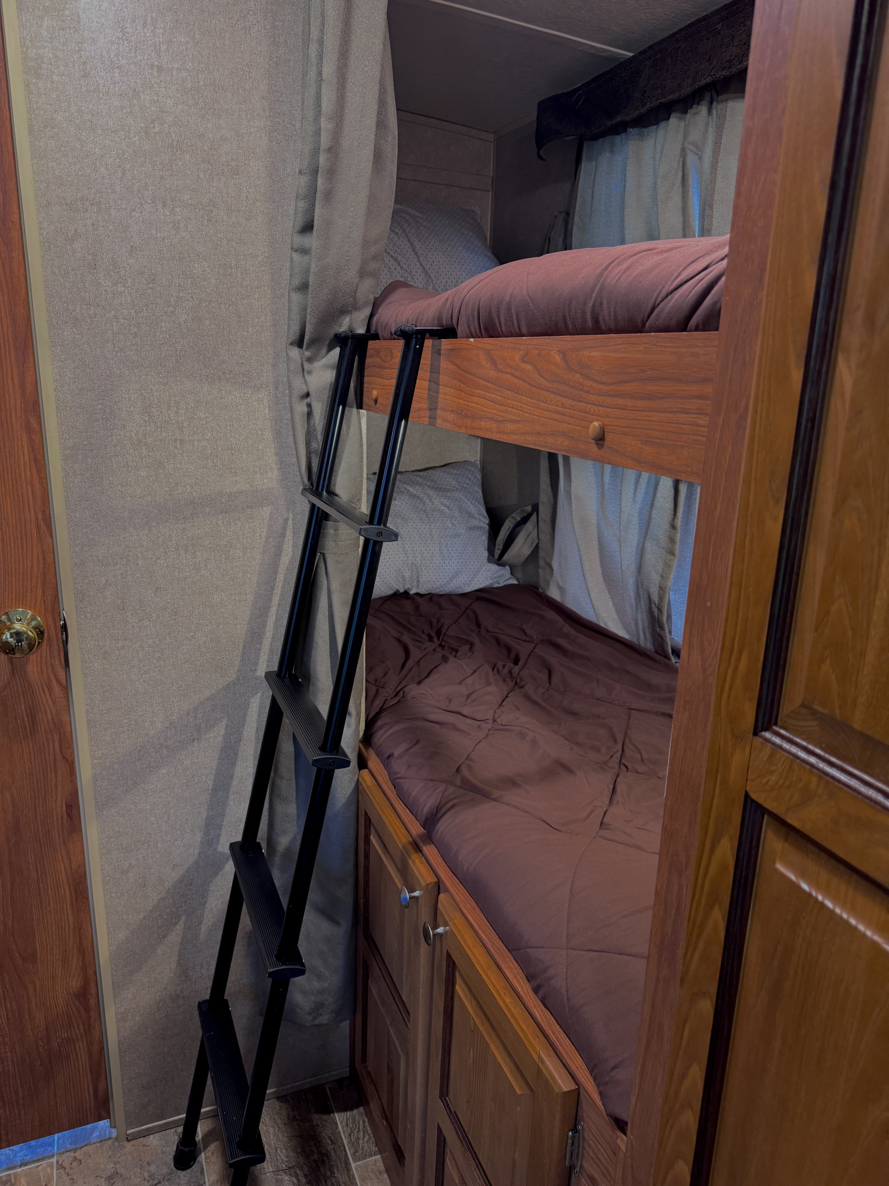 Cozy RV rental bunk beds with privacy curtains and ladder, ready for your family adventure. Comfortable sleeping space.. Forest River Rockwood Mini Lite 2016