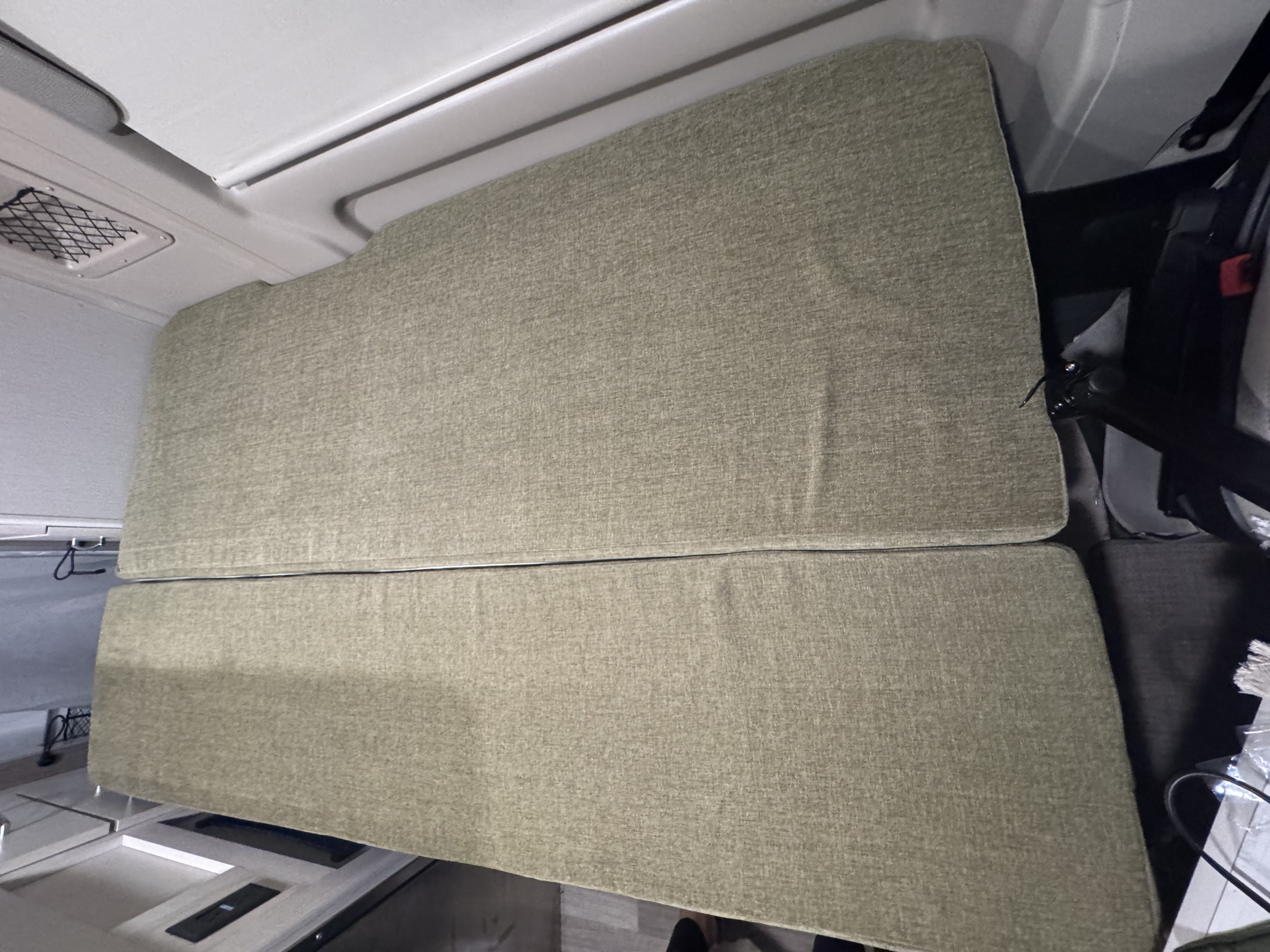 Stacked, textured green cushions create a cozy bed or seating in this RV rental. Ideal for comfortable sleep or lounging.. Thor Rize 2023
