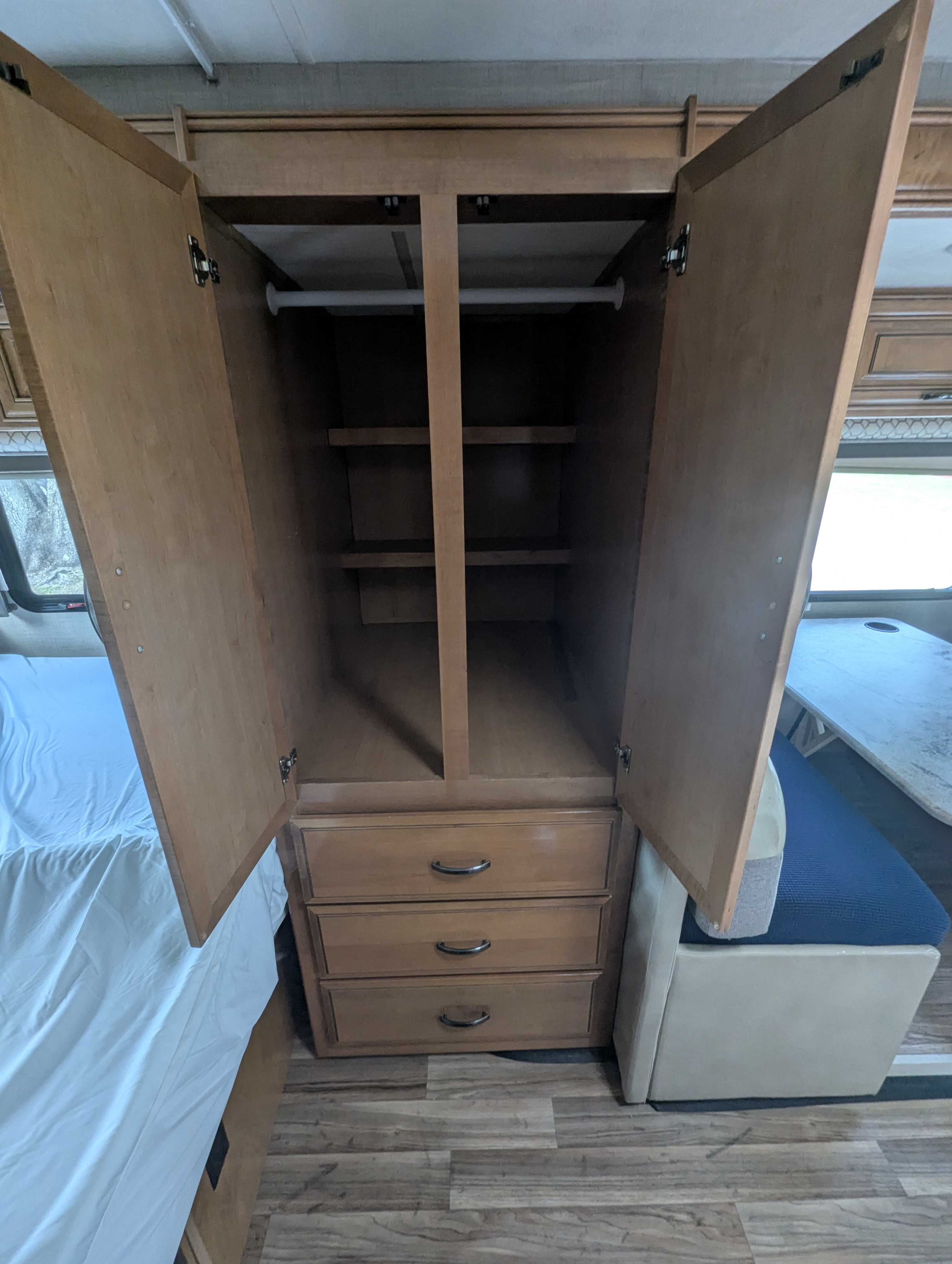 RV rental: Open wardrobe with hanging rod, shelves, and three drawers for storage. Bed and dinette visible.. Thor Motor Coach Quantum 2018