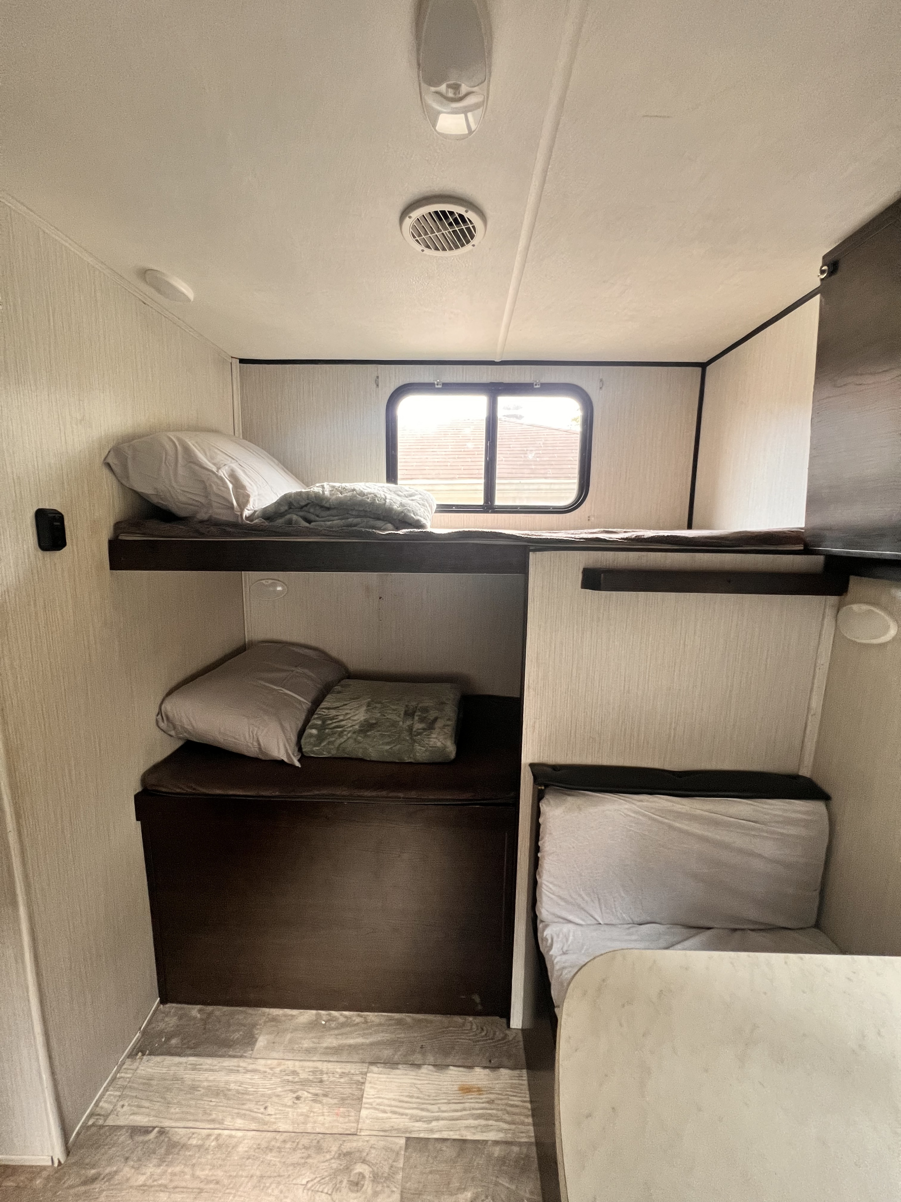 RV rental interior: A compact sleeping area with two bunk beds (top has a window), pillows, blankets, and a small table.. Heartland RVs Prowler 2021