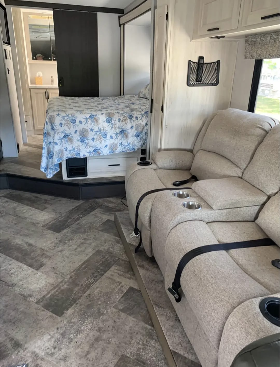 A bright rv rental interior, showcasing a raised bed with a seashell duvet, and beige recliners secured on patterned flooring.. Forester Forester Motorhome 2020
