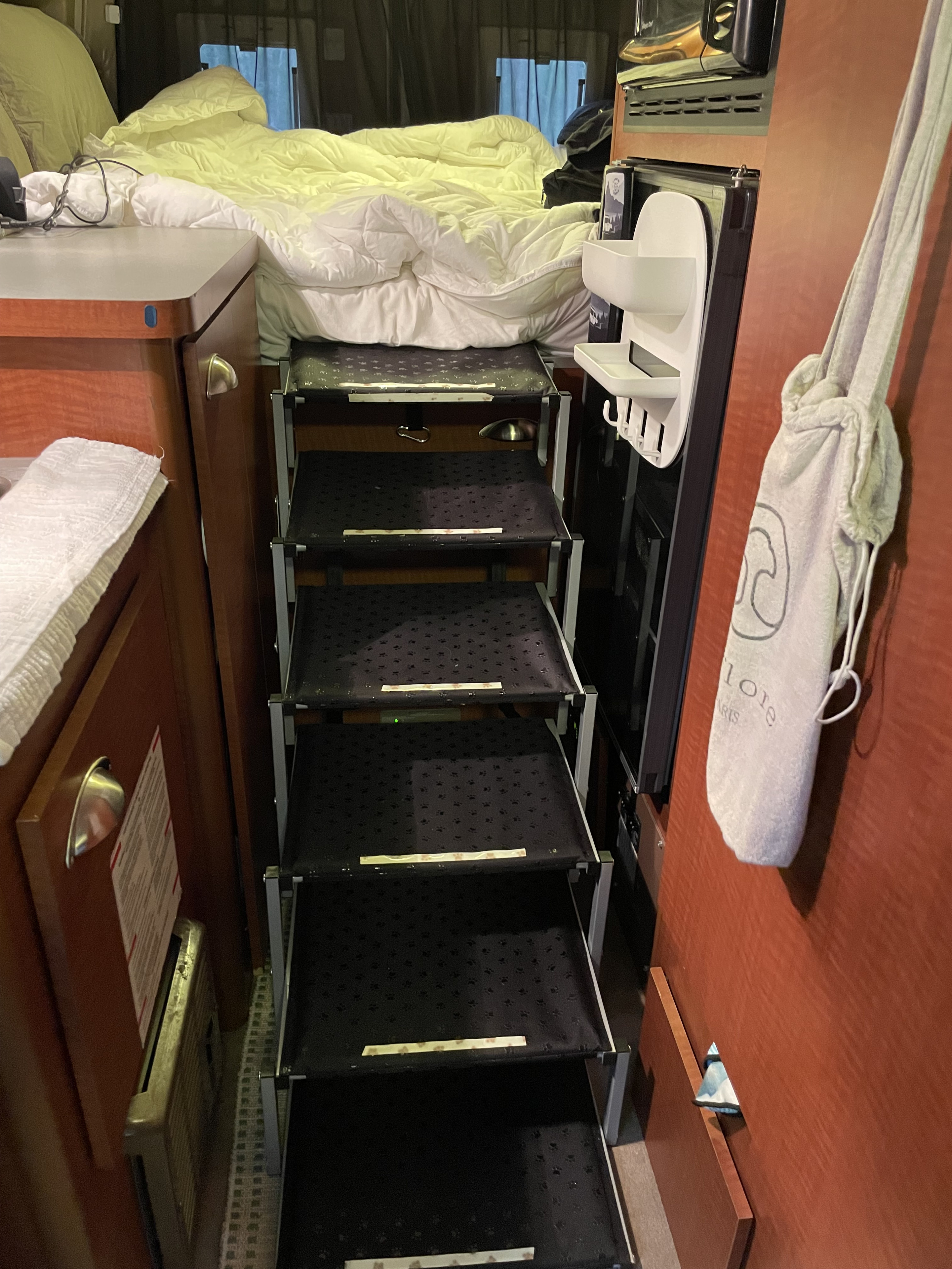 Cozy rv rental sleeping area with a bed and multi-tiered pet stairs (with paw prints). Thoughtful design for pets.. Gulf Stream Vista Cruiser 2006