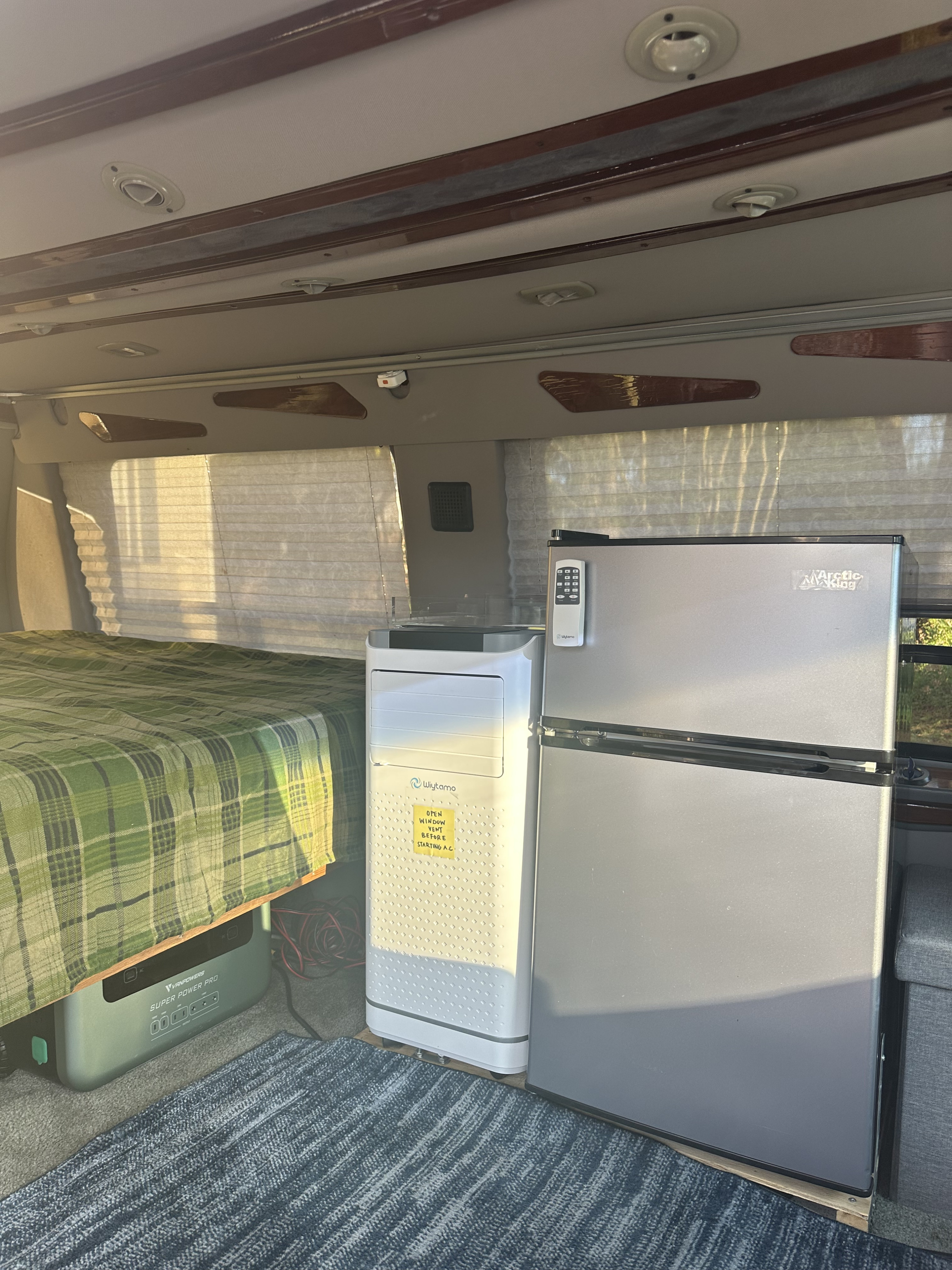 RV rental interior: cozy bed, portable AC, Arctic King fridge, and VANPOWERS power station for off-grid comfort.. Ford Econoline 150 1999