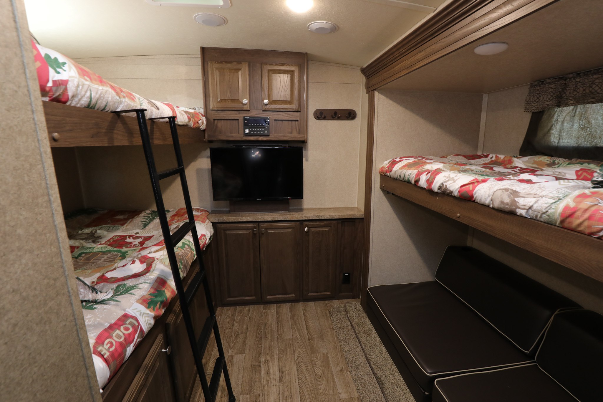 RV rental bunk room: left bunk beds with ladder, right bunk over a couch, TV, and storage cabinets, ideal for families.. Forest River Flagstaff Classic Super Lite 2018