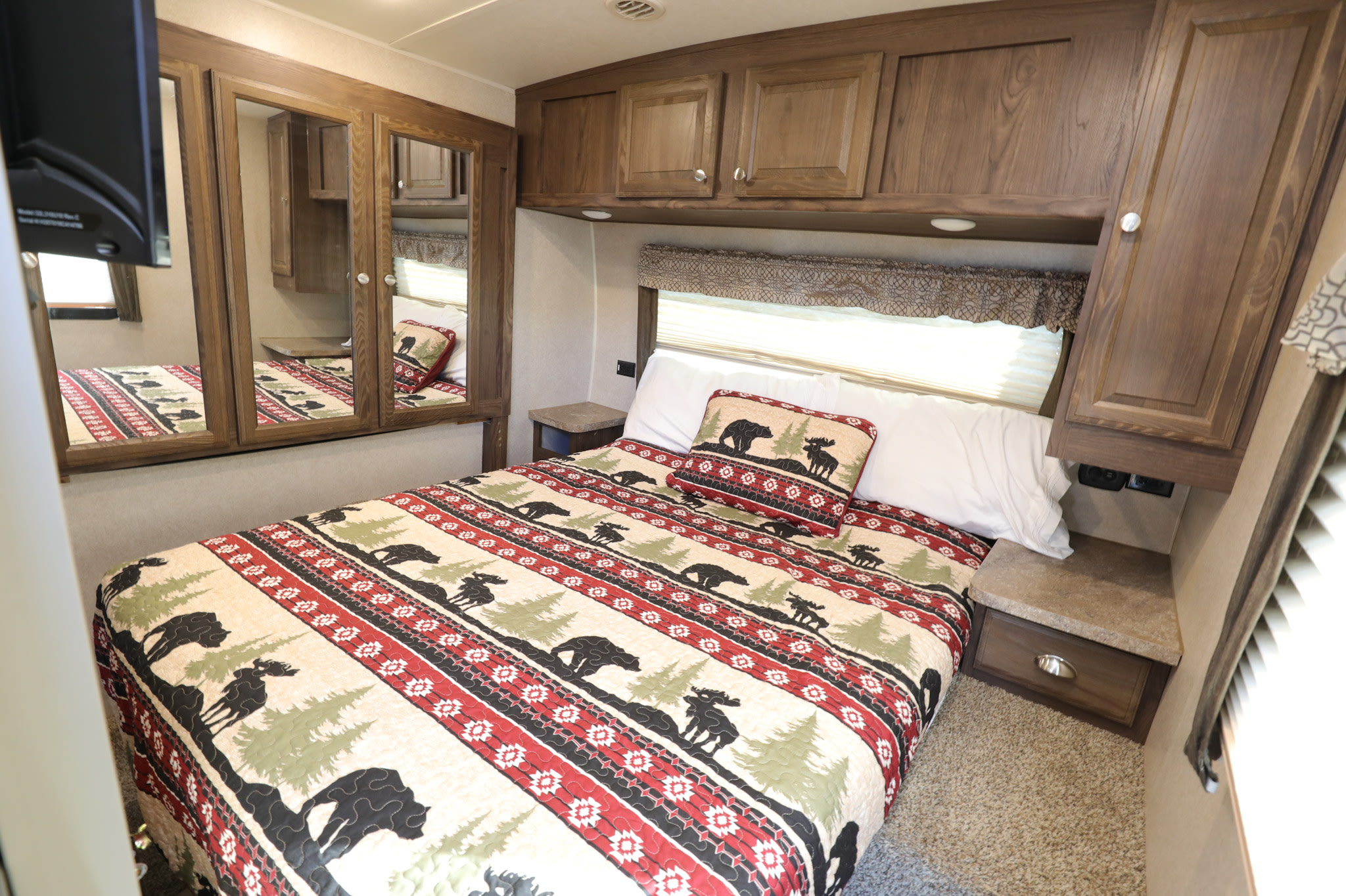 Comfortable RV rental bedroom with nature-themed bedding, overhead cabinets, and mirrored wardrobes for storage.. Forest River Flagstaff Classic Super Lite 2018