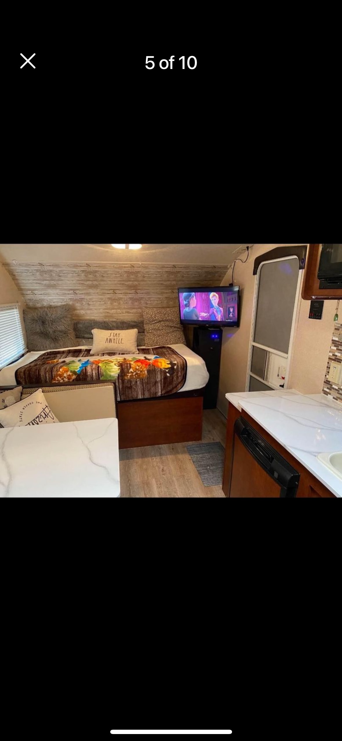 Explore this cozy rv rental interior! Features a bed with shiplap-style wall, TV, and compact kitchen with marble-look counter.. Forest River Flagstaff E-Pro 2017
