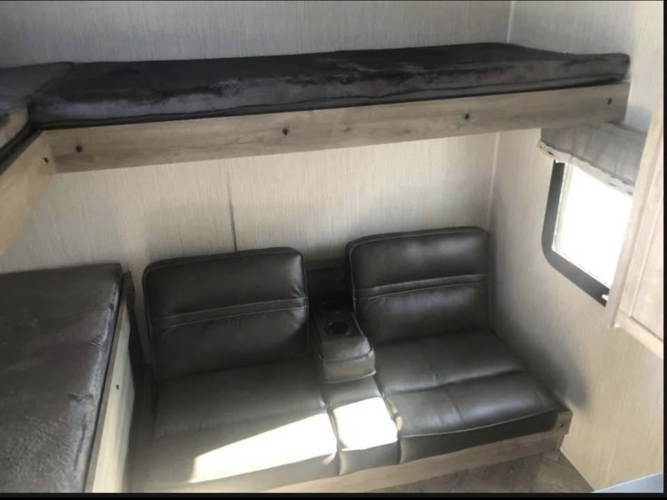 Cozy RV rental interior featuring bunk beds, comfortable seating with cup holders, and a window.. Forest River Palomino Puma 2022