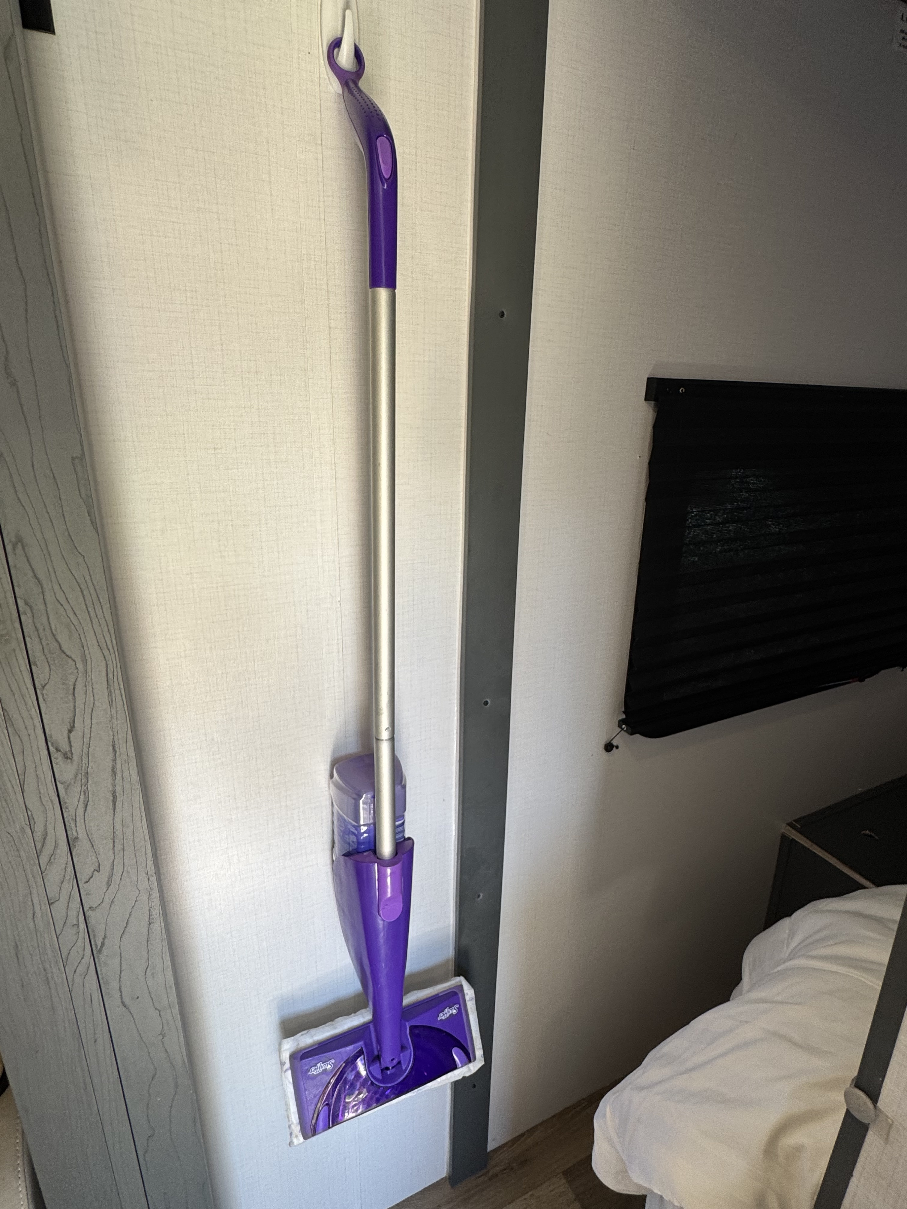 A Swiffer WetJet mop hangs neatly on the wall of an RV rental, ready for efficient cleaning in compact living spaces.. Keystone RV Bullet Ultra Lite 2022