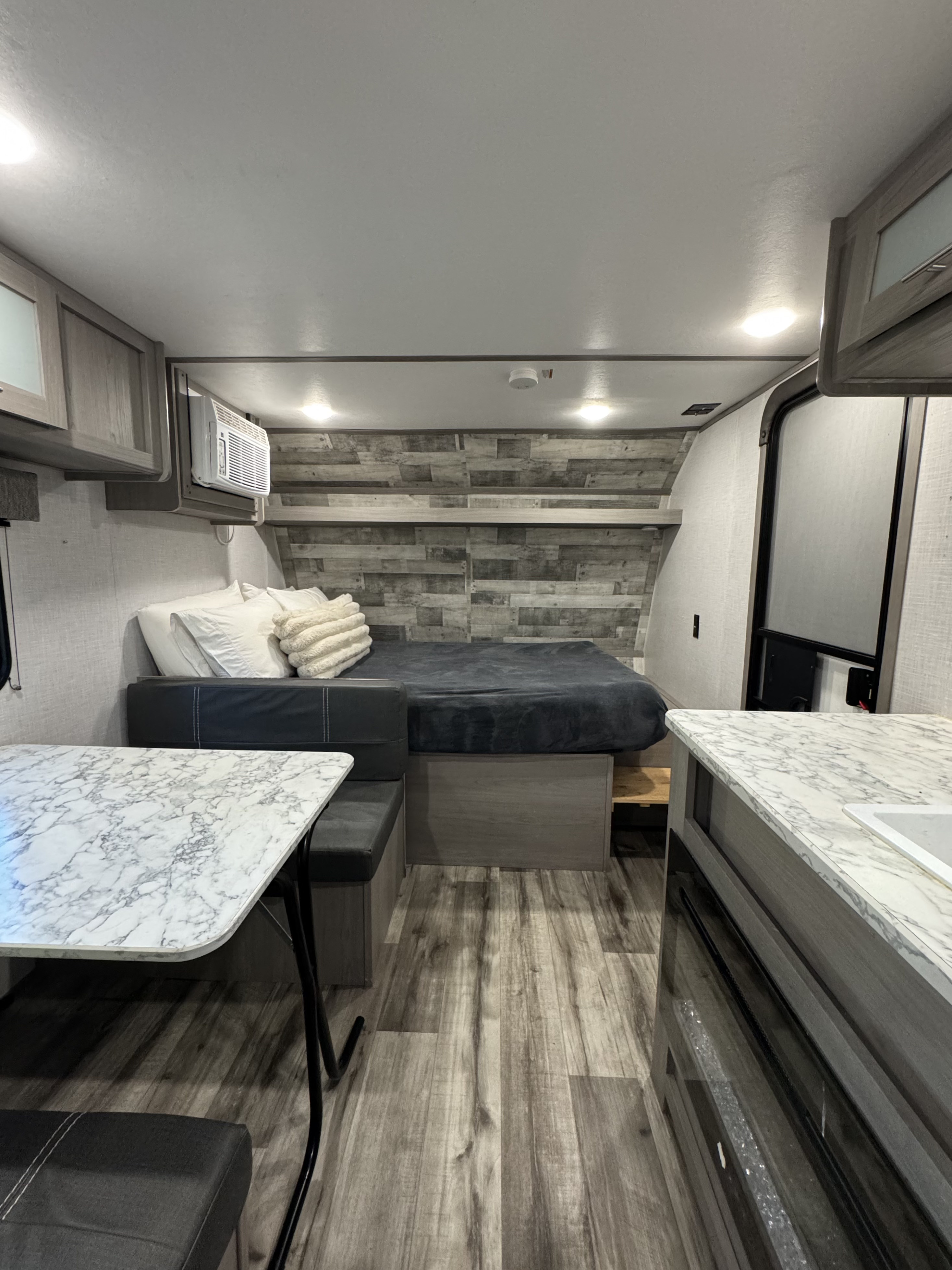 Explore this rv rental's interior: a comfortable bed, dinette with marble-top table, compact kitchen, and wood-look flooring.. Dutchmen Coleman Lantern 2022