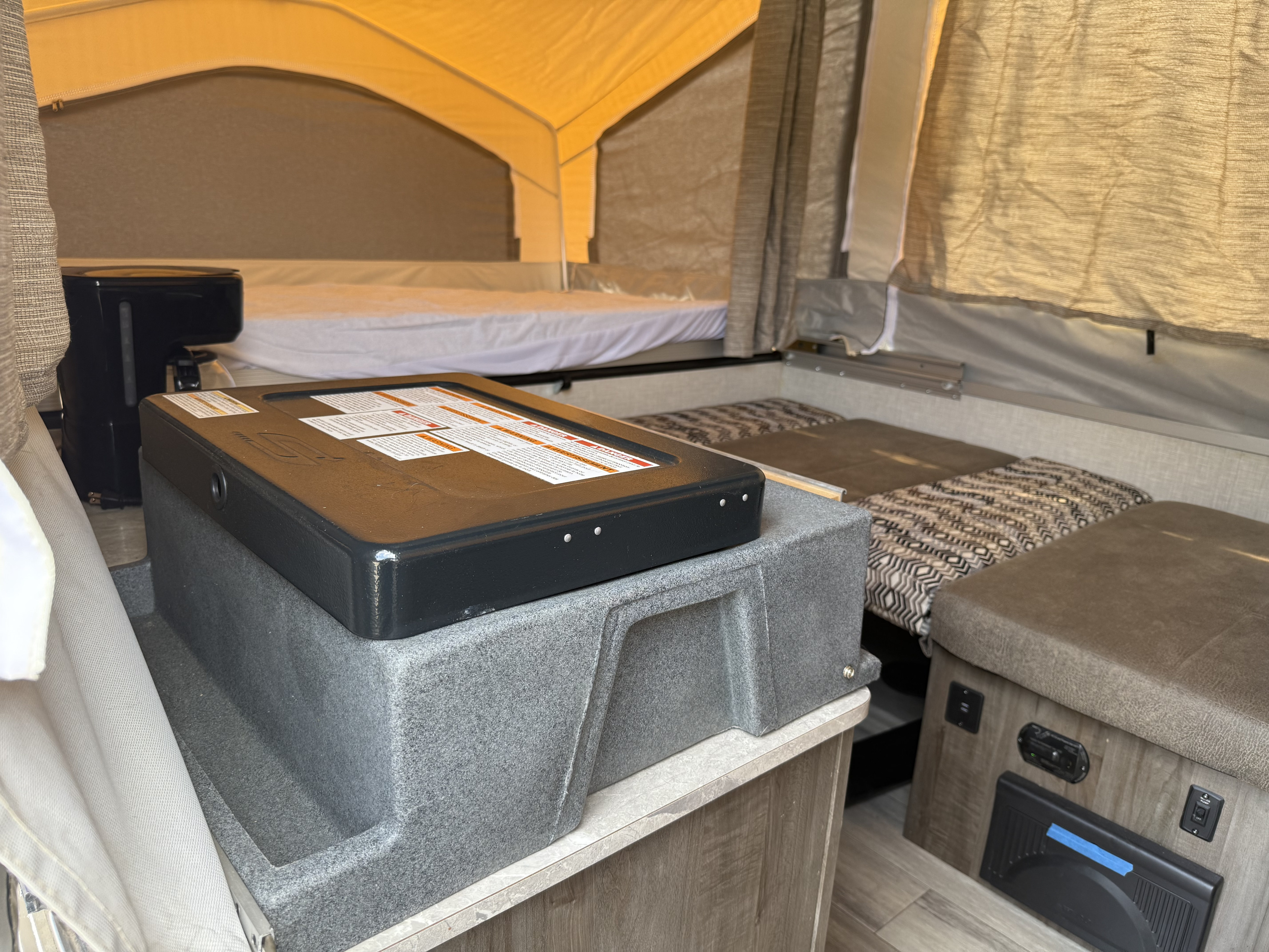 Inside a cozy rv rental pop-up camper with beds, a coffee maker, and a portable stove on a counter.. Forest River Flagstaff M.A.C. 2022