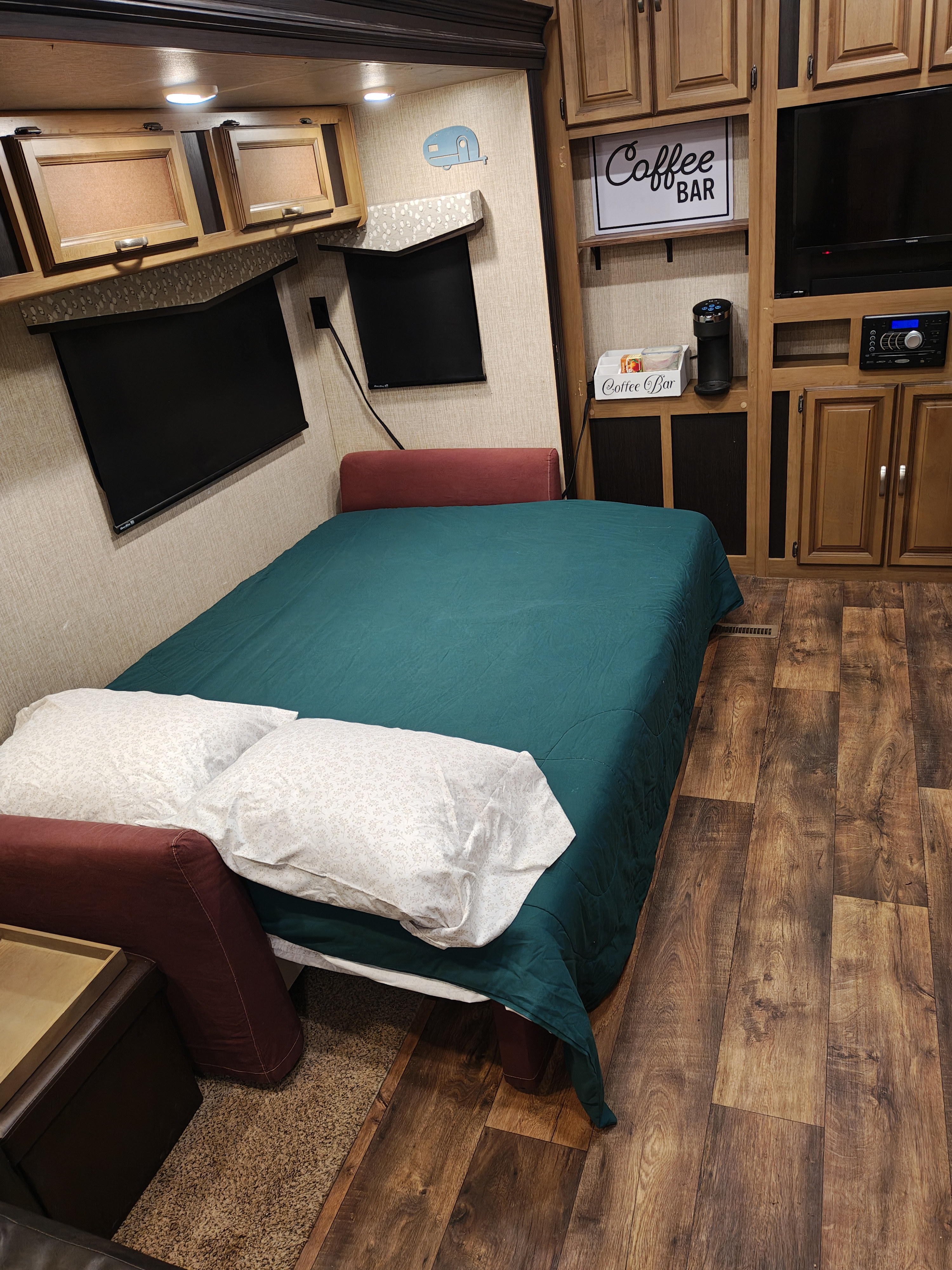 Comfortable rv rental interior: inviting bed with teal comforter, handy coffee bar, TV, and warm wood accents.. Crossroads RV Cruiser Aire 2017