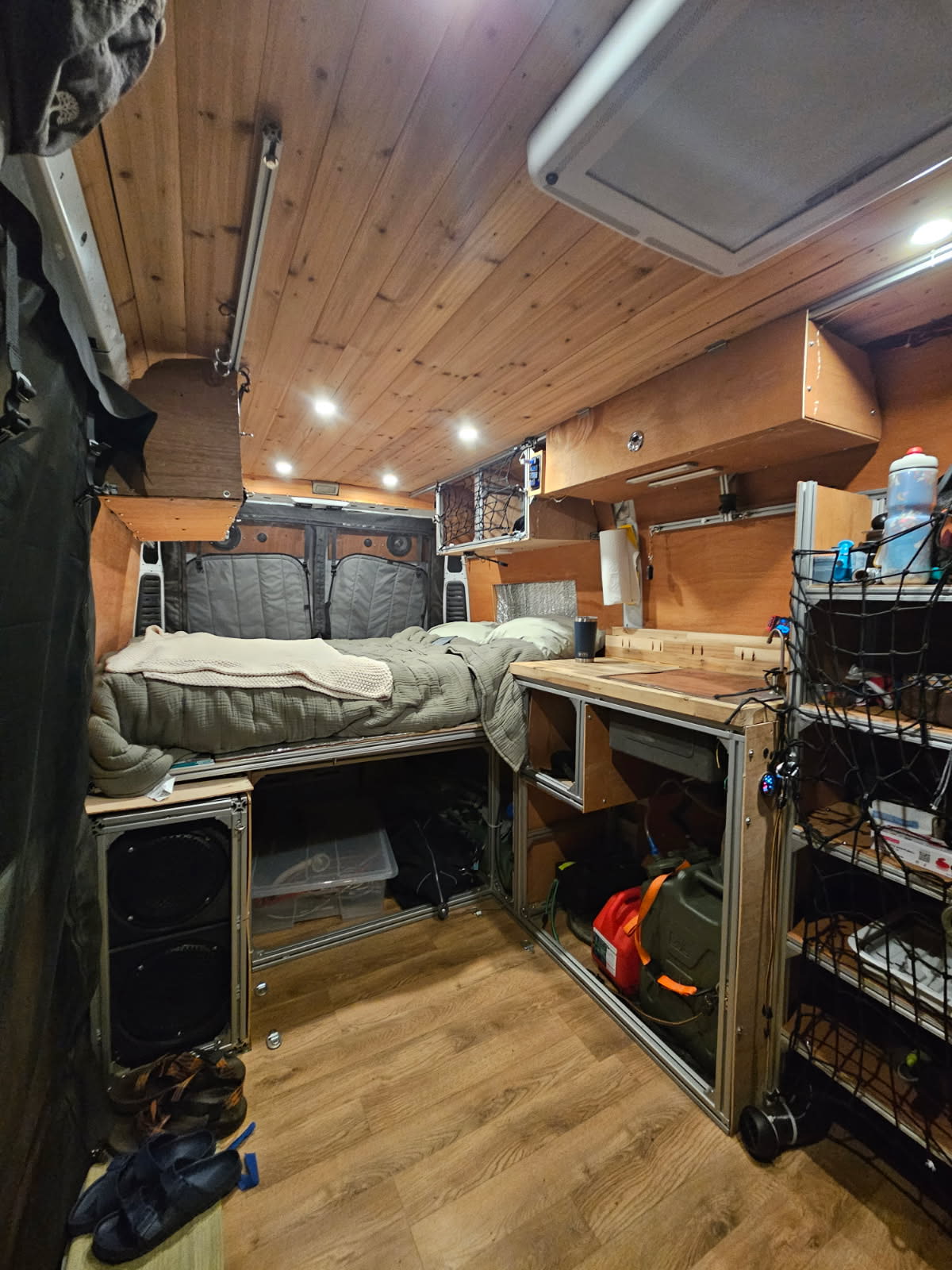 Cozy custom RV rental interior features a raised bed, compact kitchen, and organized storage beneath a wooden ceiling.. Dodge Ram 1500 2019