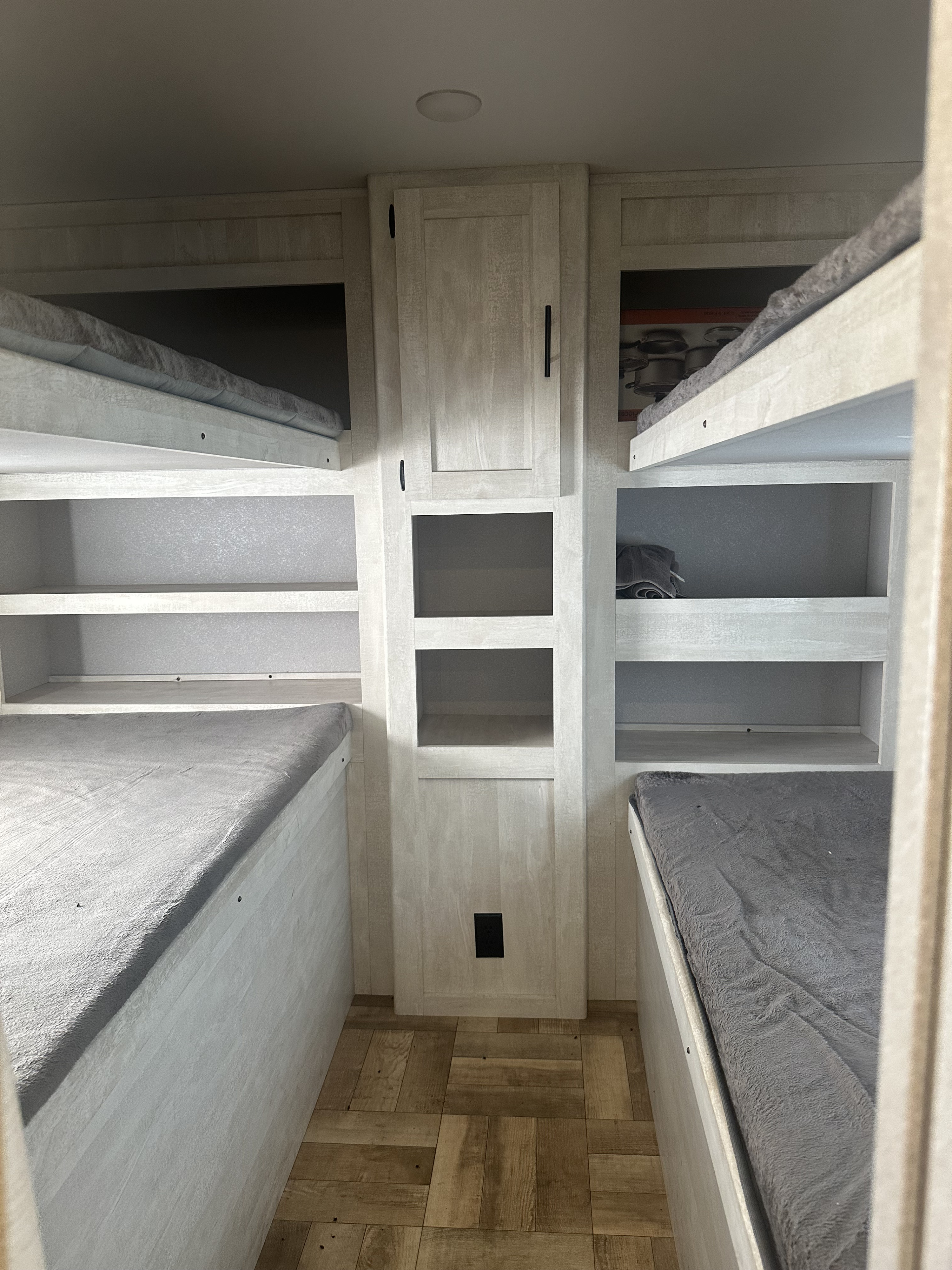RV rental interior: A bright space with two sets of bunk beds, grey mattresses, and central shelving for storage.. Forest River Shasta 2023