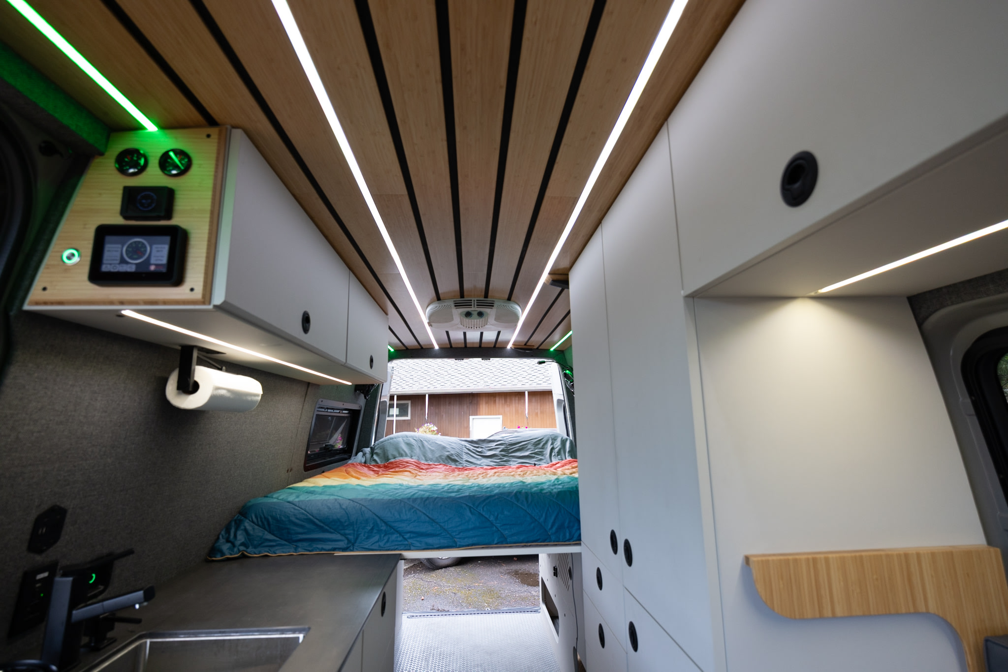 Explore this modern rv rental camper van interior: sleek wood ceiling, tech controls, compact kitchen, and cozy bed.. Mercedes-Benz Sprinter 2022