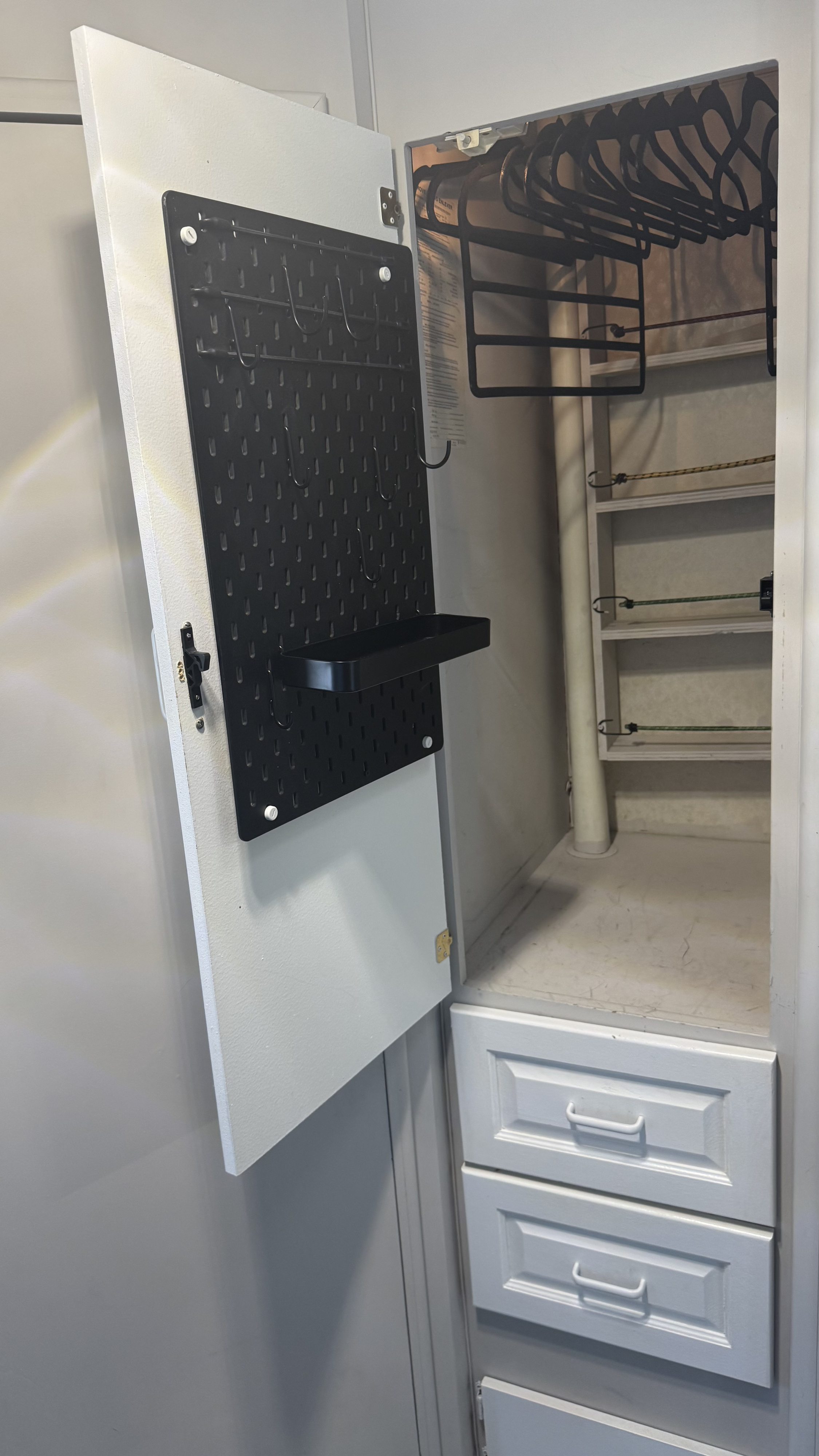 This RV rental offers organized storage: an open closet with a pegboard door, hangers, bungee-secured shelves, and drawers.. Ford E350 Box Van 1992