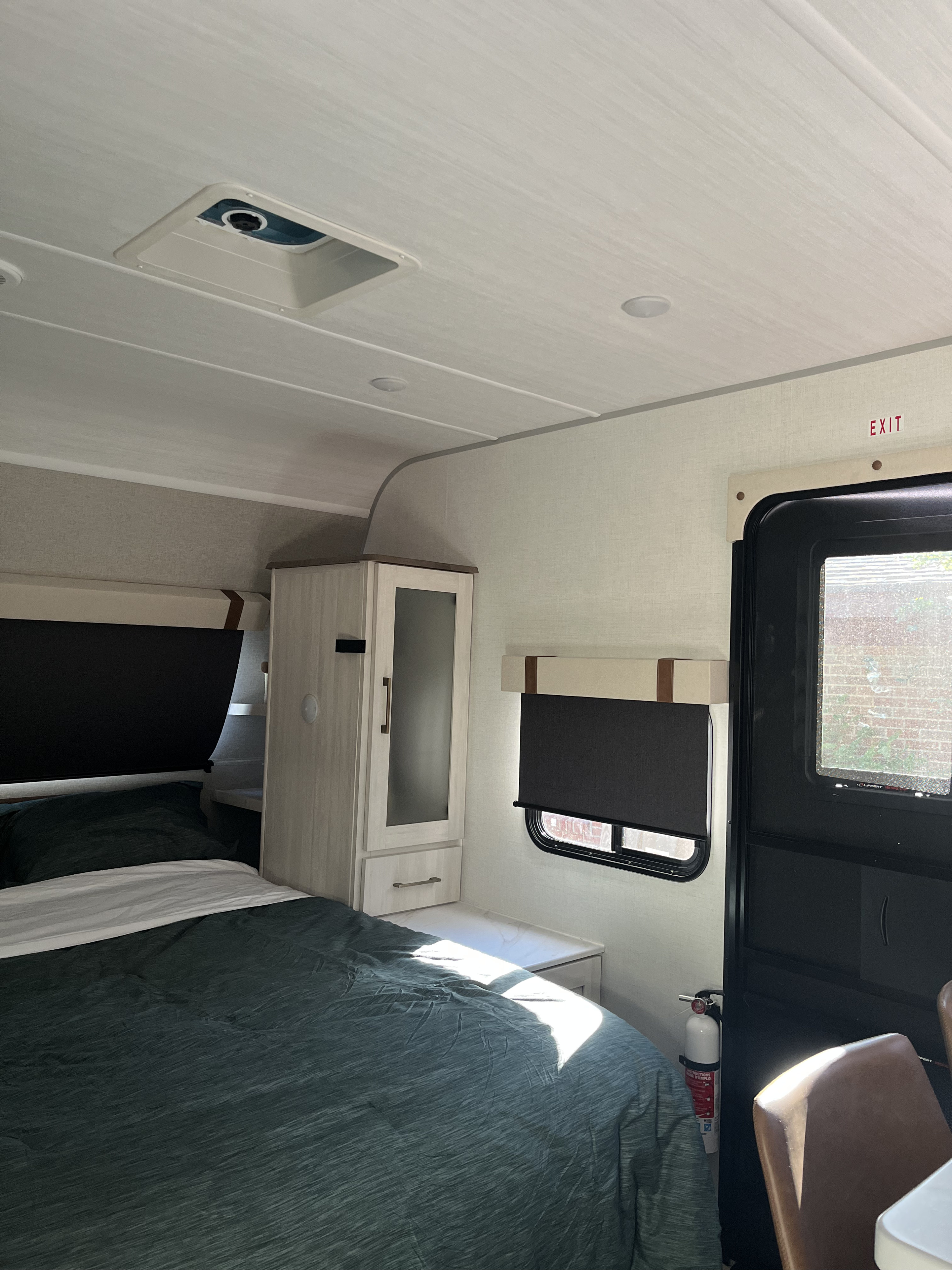 RV rental interior: A bright, modern bedroom area with a green bed, storage, window, & safety exit.. Forest River 5NHTRDV27TD211453 2026